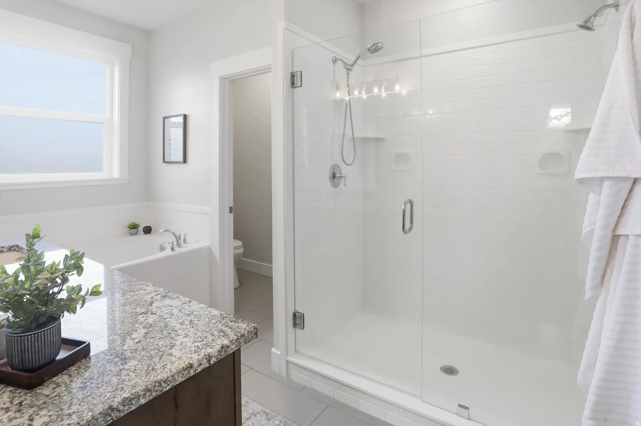 master bathroom featuring light tile patterned flooring, vanity, a dual shower stall, and a bath