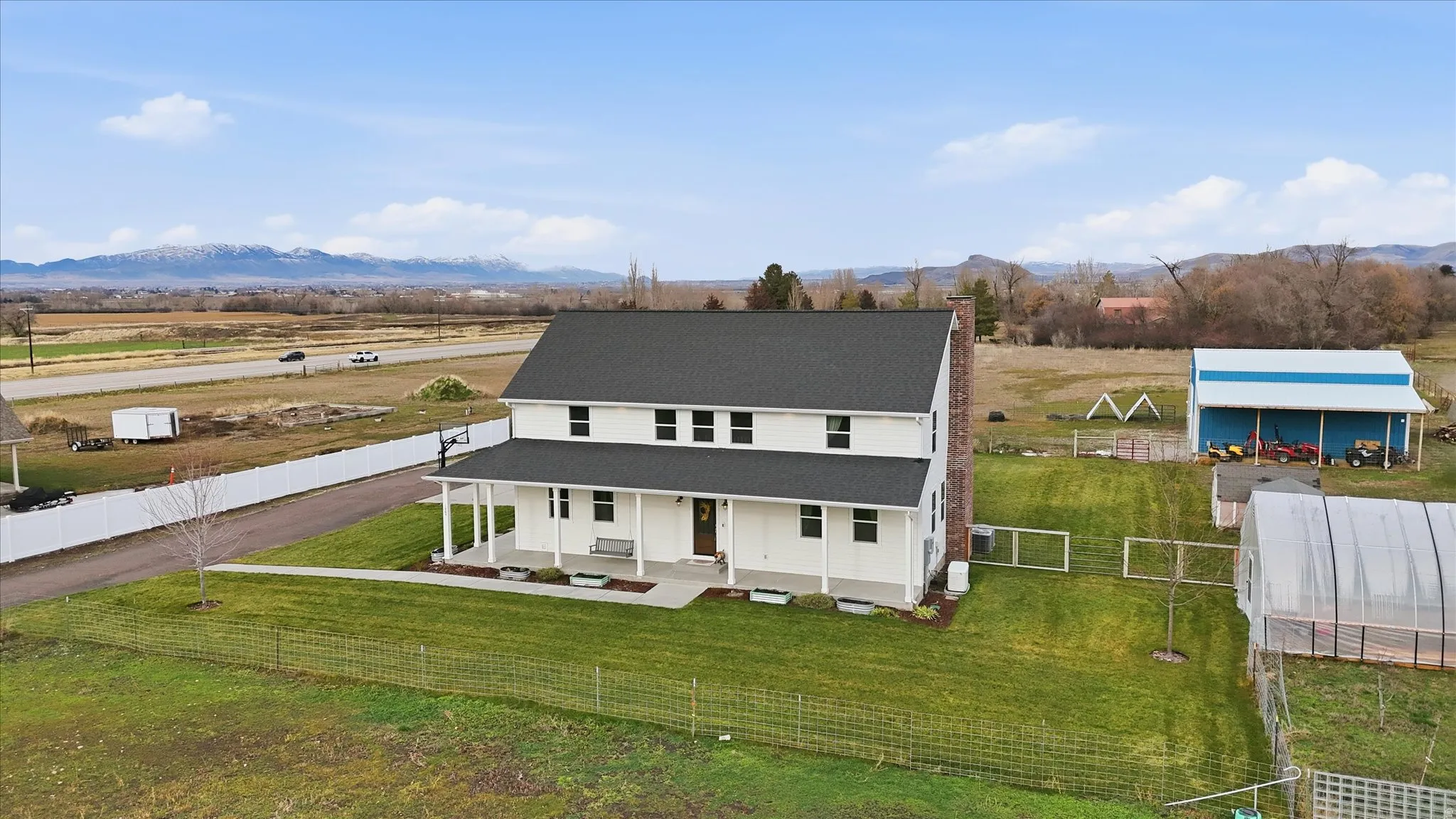 View of front of property featuring covered porch, a fenced backyard, a rural view, a chimney, and a mountain view