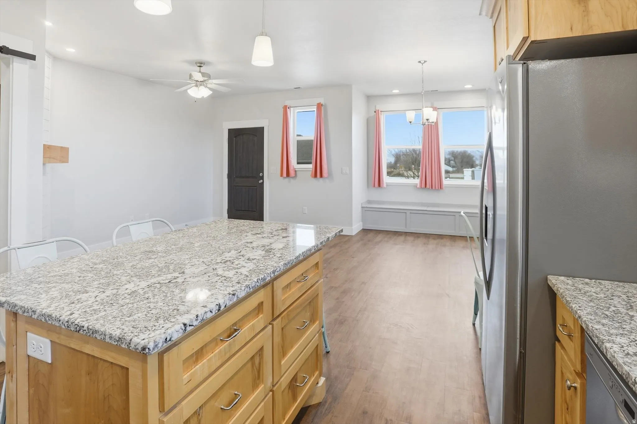 ADU Kitchen with stainless steel appliances, light stone counters, pendant lighting, a kitchen island, and dark wood-type flooring
