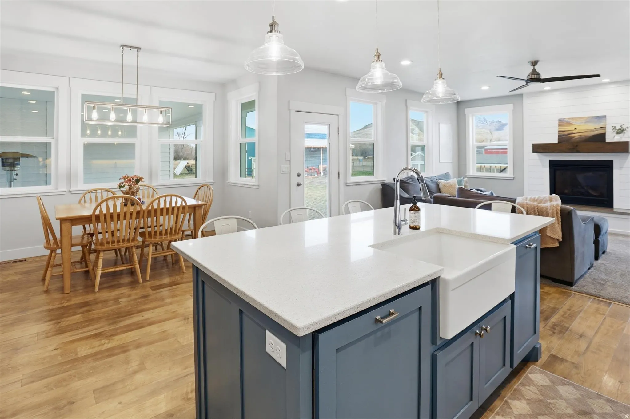 Kitchen featuring blue cabinetry, hanging light fixtures, light wood-type flooring, light stone counters, and open floor plan