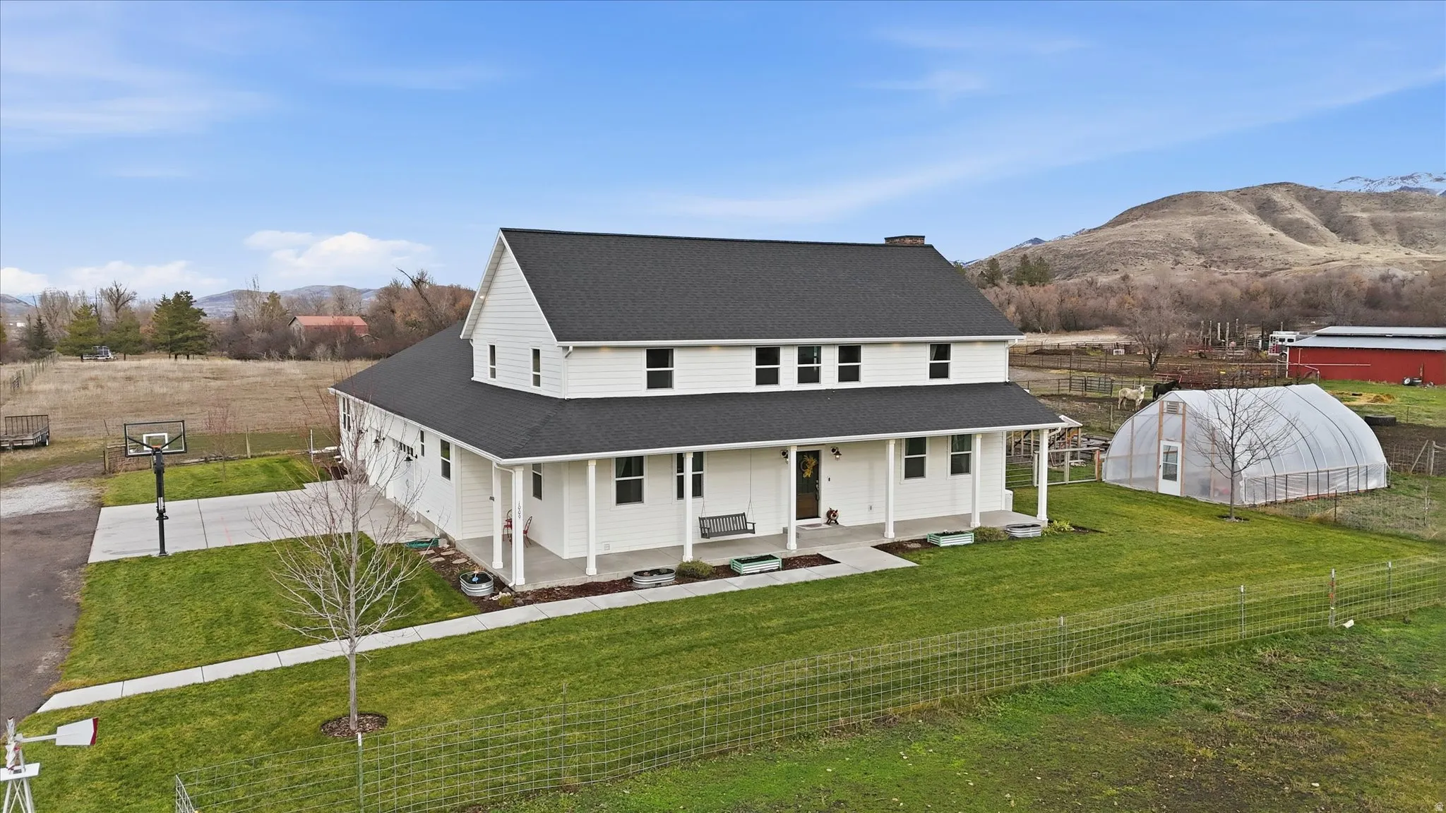 Country-style home with covered porch, driveway, a front lawn, a greenhouse, and roof with shingles