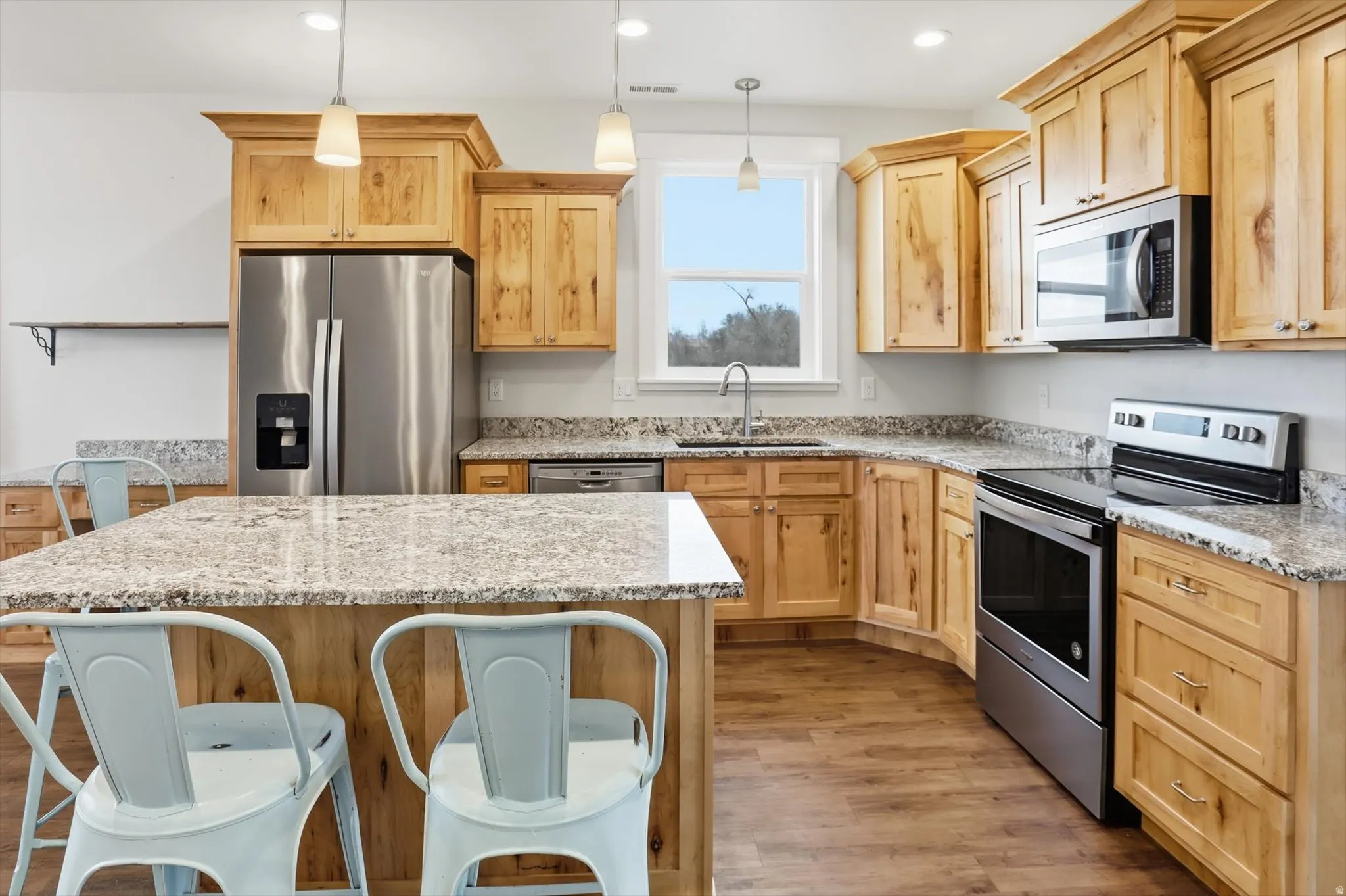 ADU Kitchen with stainless steel appliances, a kitchen bar, light brown cabinetry, light wood-style flooring, and recessed lighting