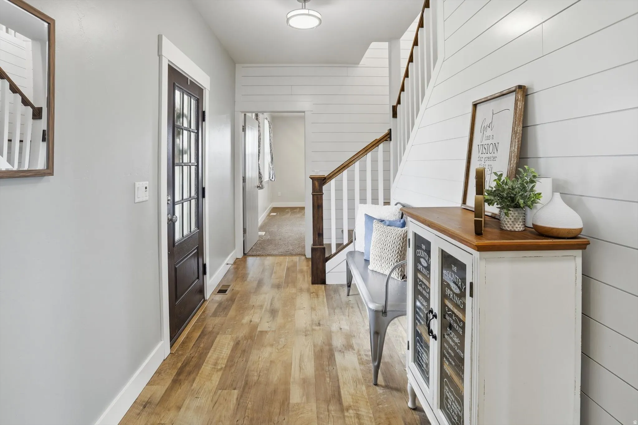 Foyer entrance featuring stairs, light wood-style floors, and wooden walls