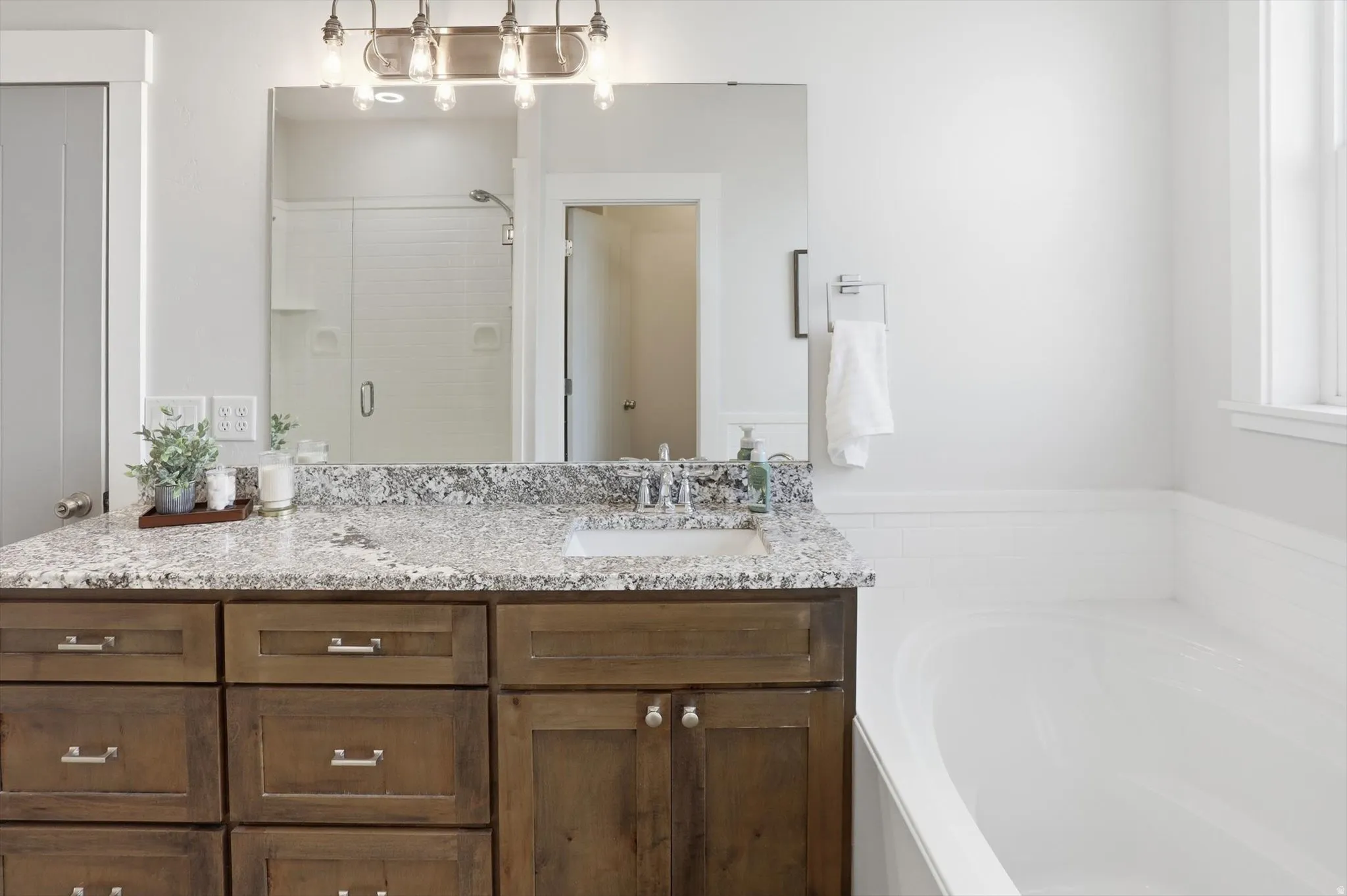 Full bath with a stall shower, vanity, and a garden tub