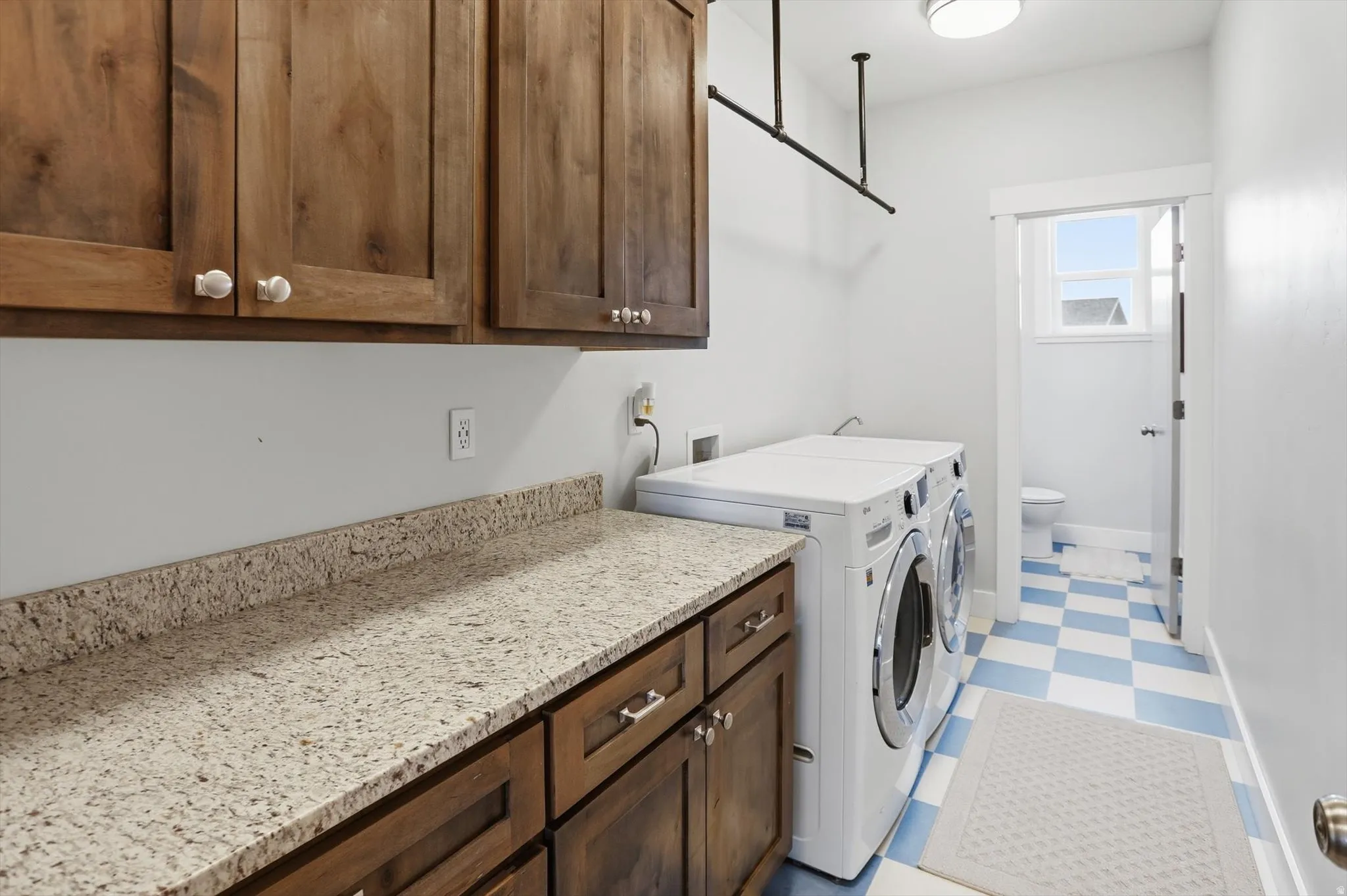 Laundry room featuring light flooring, separate washer and dryer, and cabinet space