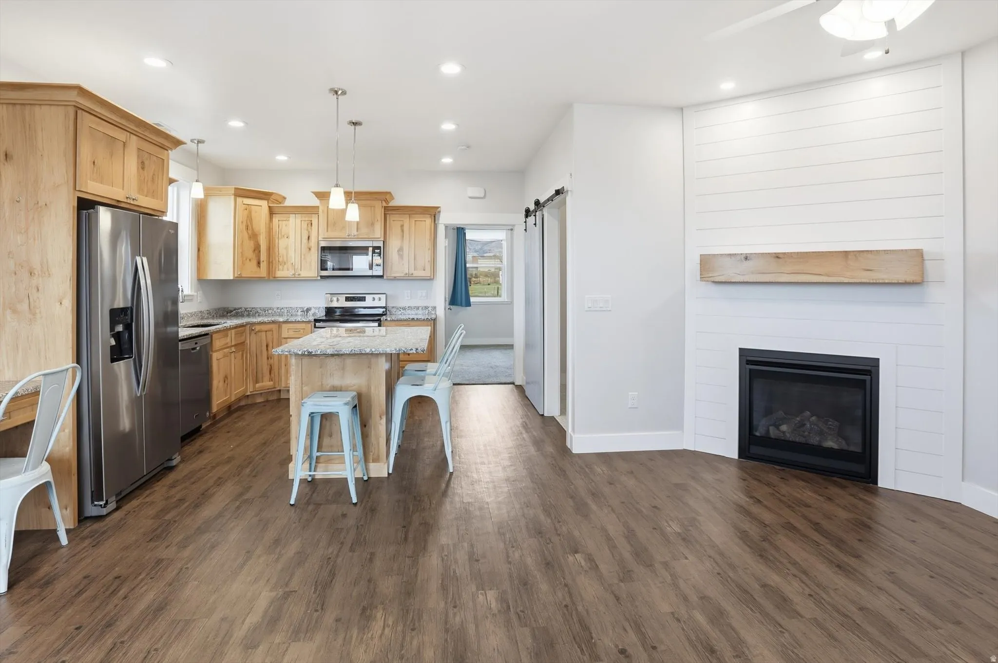 ADU Kitchen with a barn door, hanging light fixtures, stainless steel appliances, a center island, and a kitchen breakfast bar