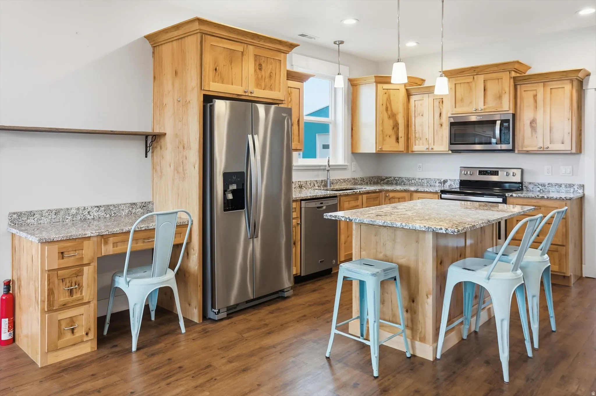 ADU Kitchen with stainless steel appliances, light stone countertops, a breakfast bar area, a kitchen island, and pendant lighting