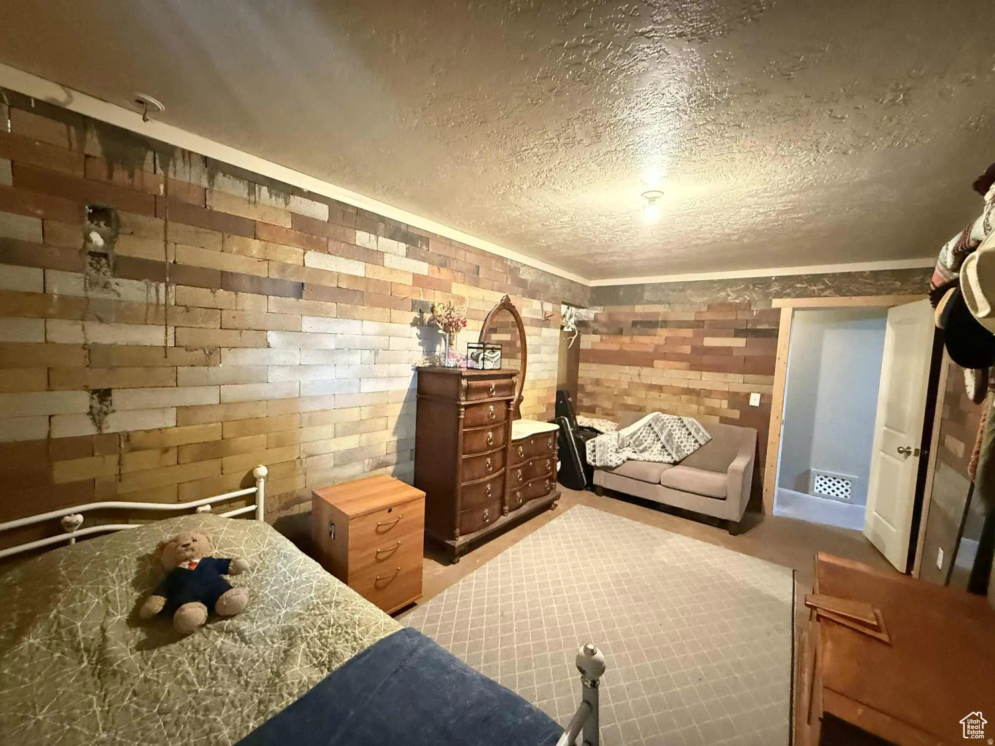 Bedroom with a textured ceiling and brick wall