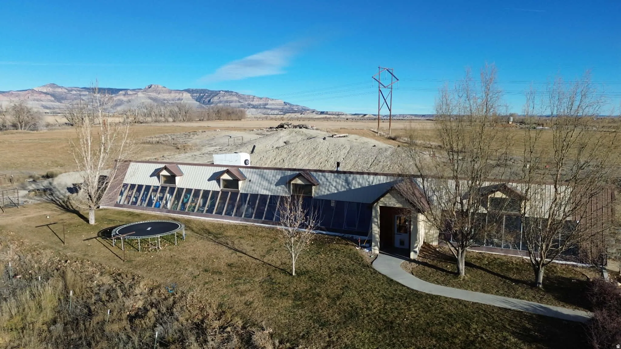 View of front of property with a trampoline, a front lawn, a mountain view, and a view of rural / pastoral area