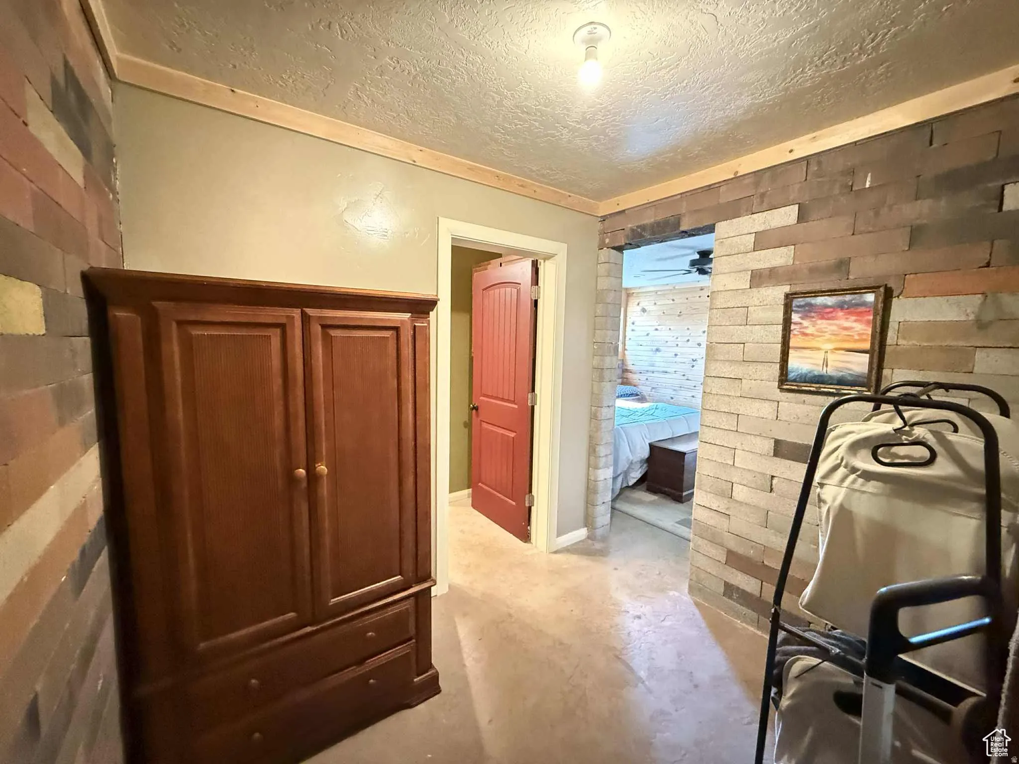 Hall with concrete flooring, a textured ceiling, and brick wall