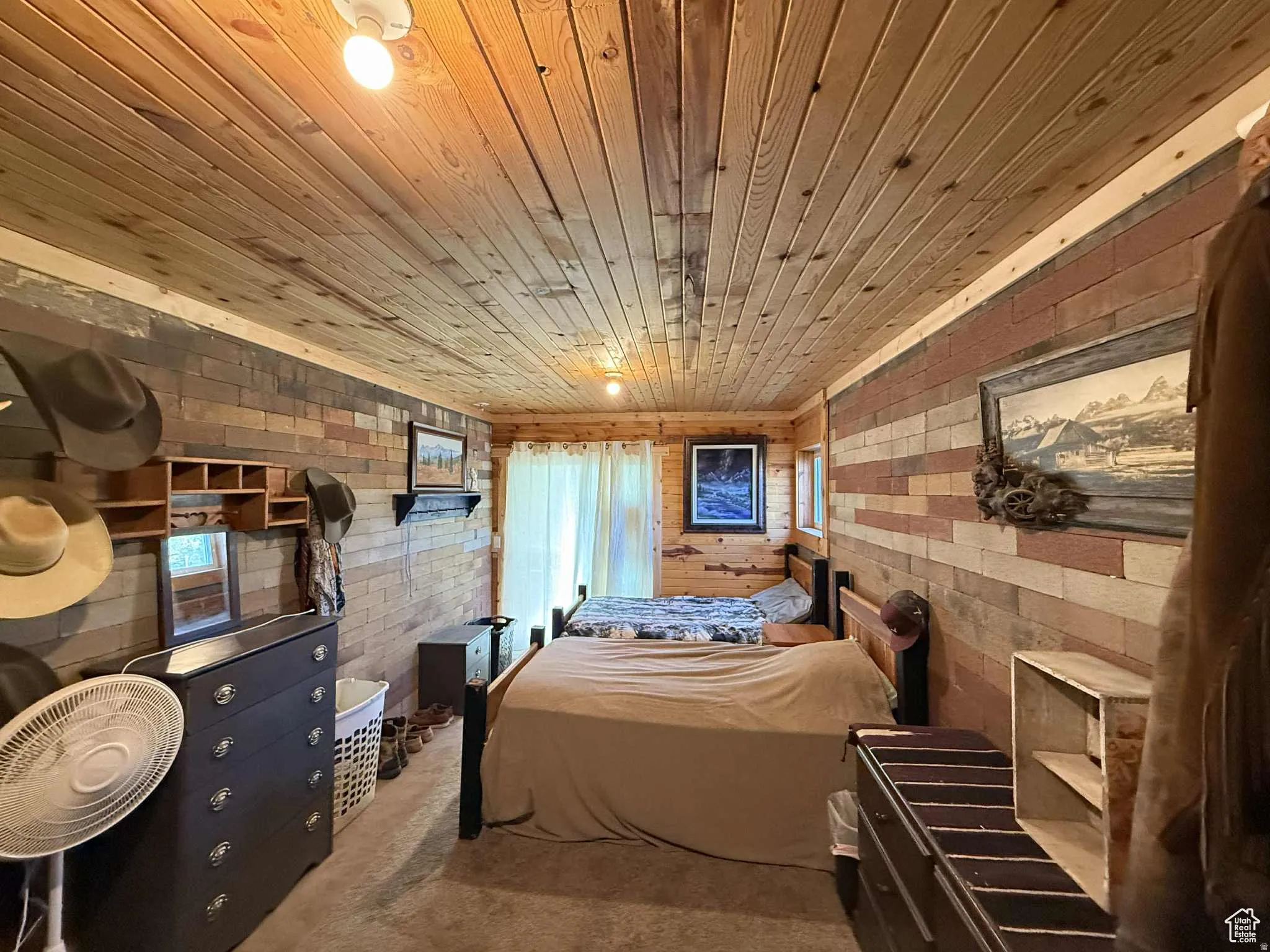 Bedroom with wood ceiling, brick wall, and carpet floors
