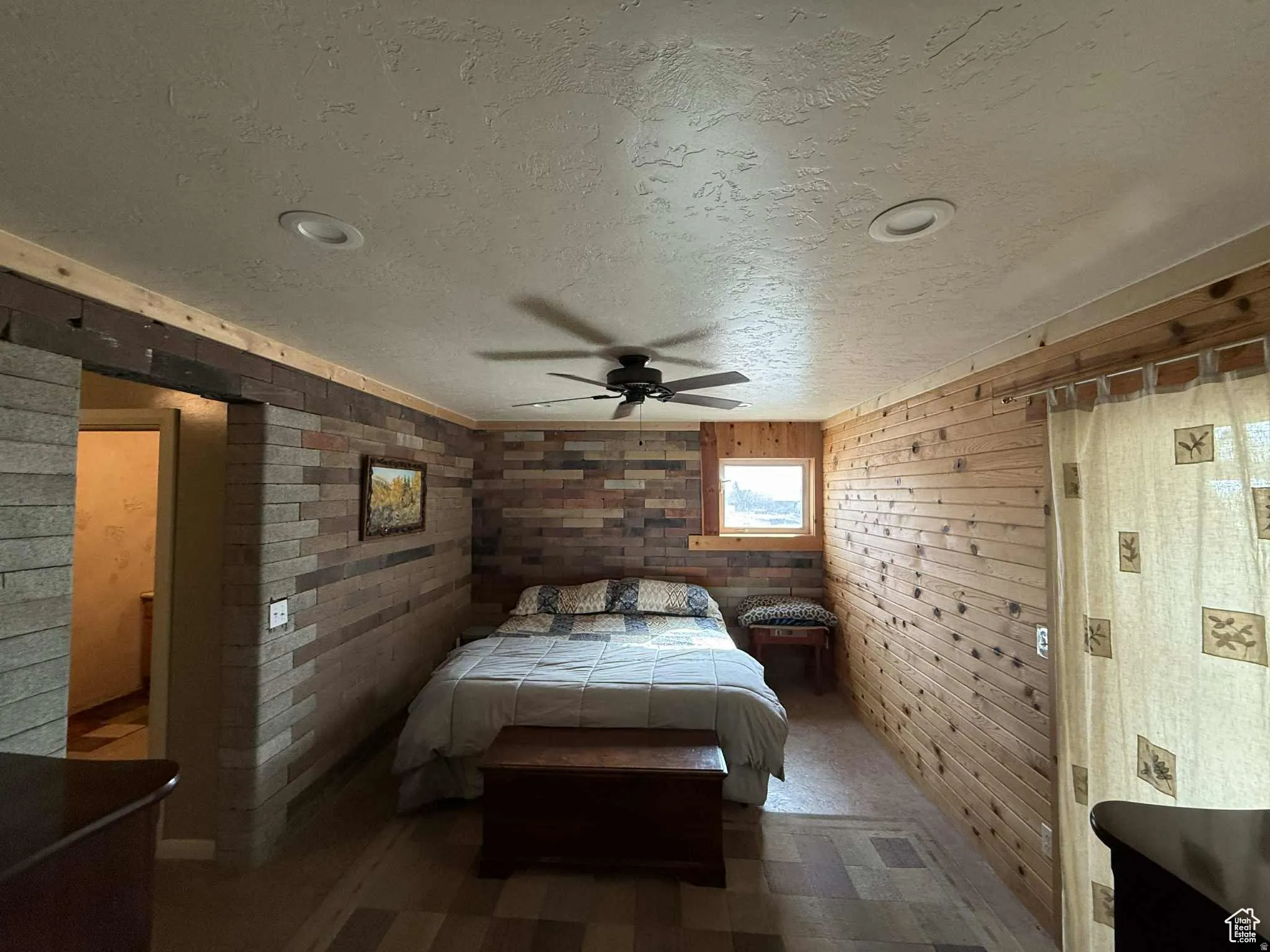 Bedroom featuring a textured ceiling, wood walls, ceiling fan, and tile patterned floors