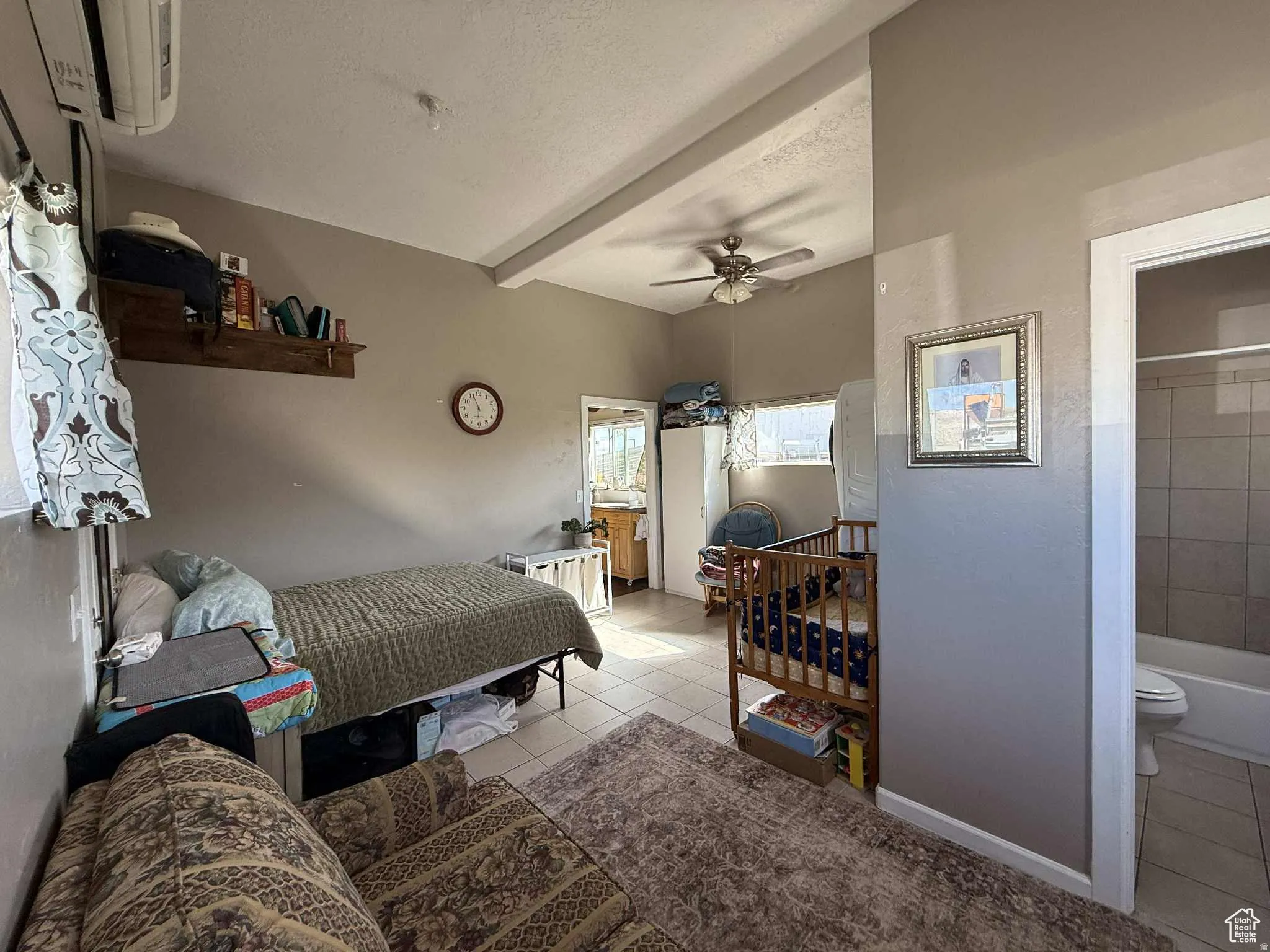 Bedroom with connected bathroom, tile patterned floors, a textured ceiling, a ceiling fan, and beamed ceiling