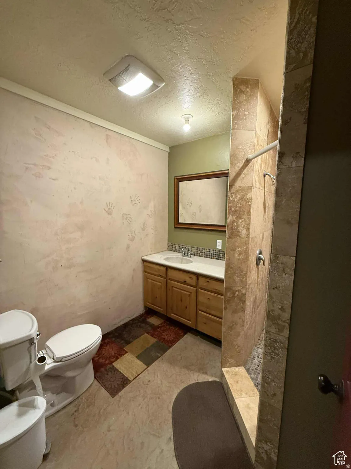 Bathroom featuring a walk in shower, a textured ceiling, and vanity