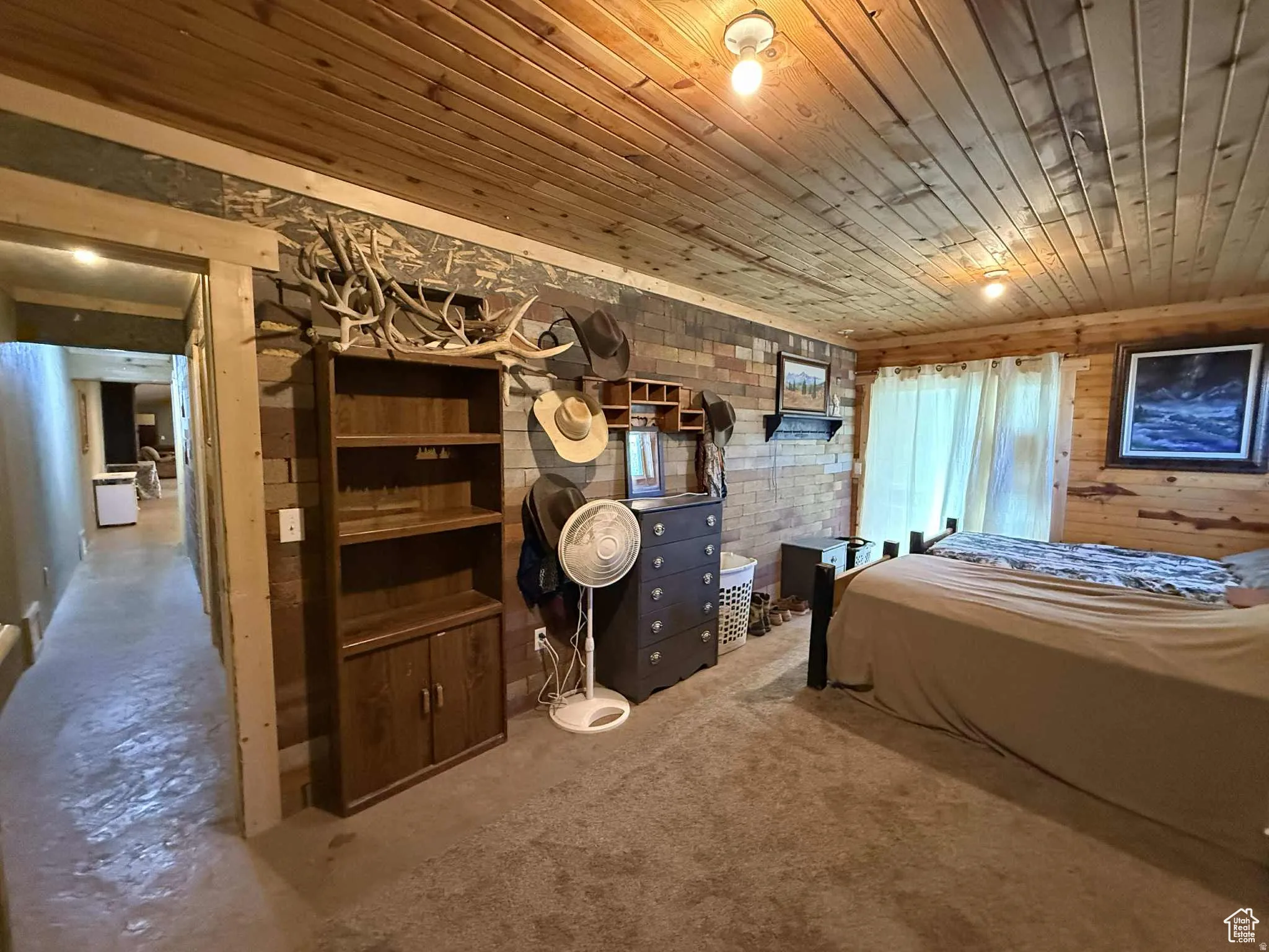 Bedroom featuring wooden ceiling, unfinished concrete floors, wood walls, and brick wall