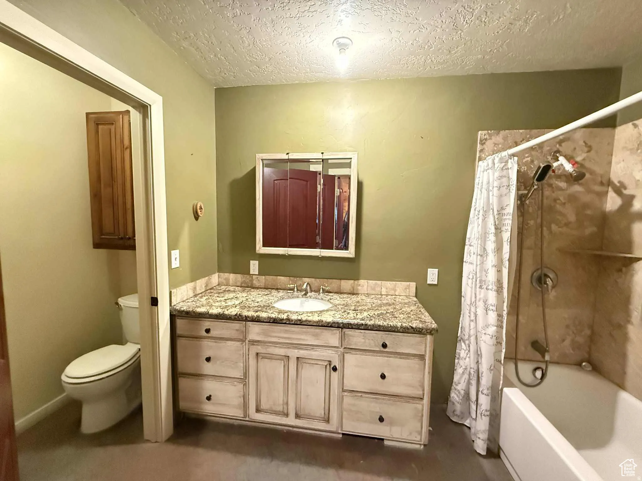 Full bathroom with vanity, shower / bath combo with shower curtain, a textured ceiling, and concrete floors