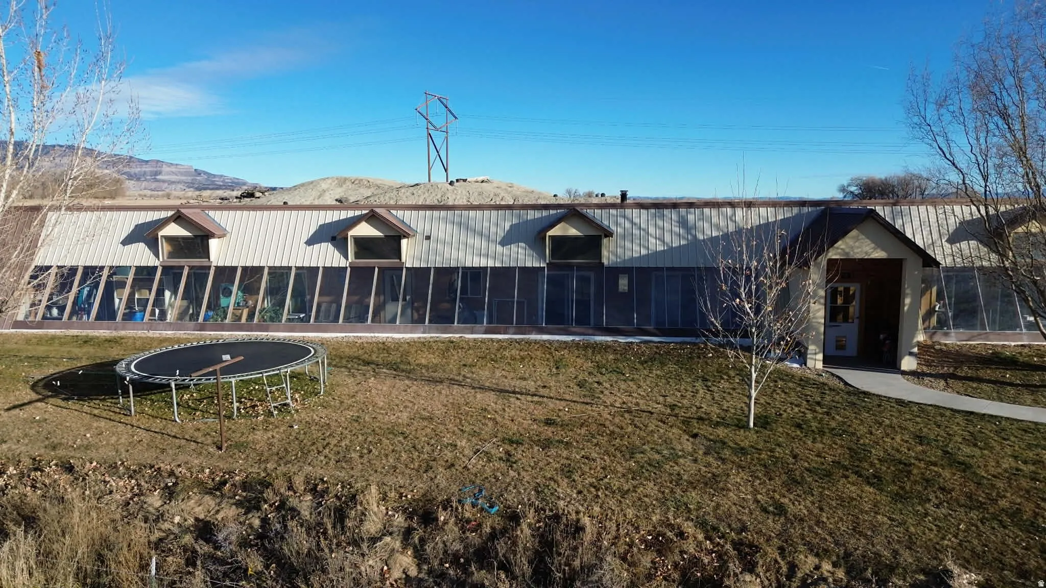 Rear view of house featuring a yard, a trampoline, and a mountain view