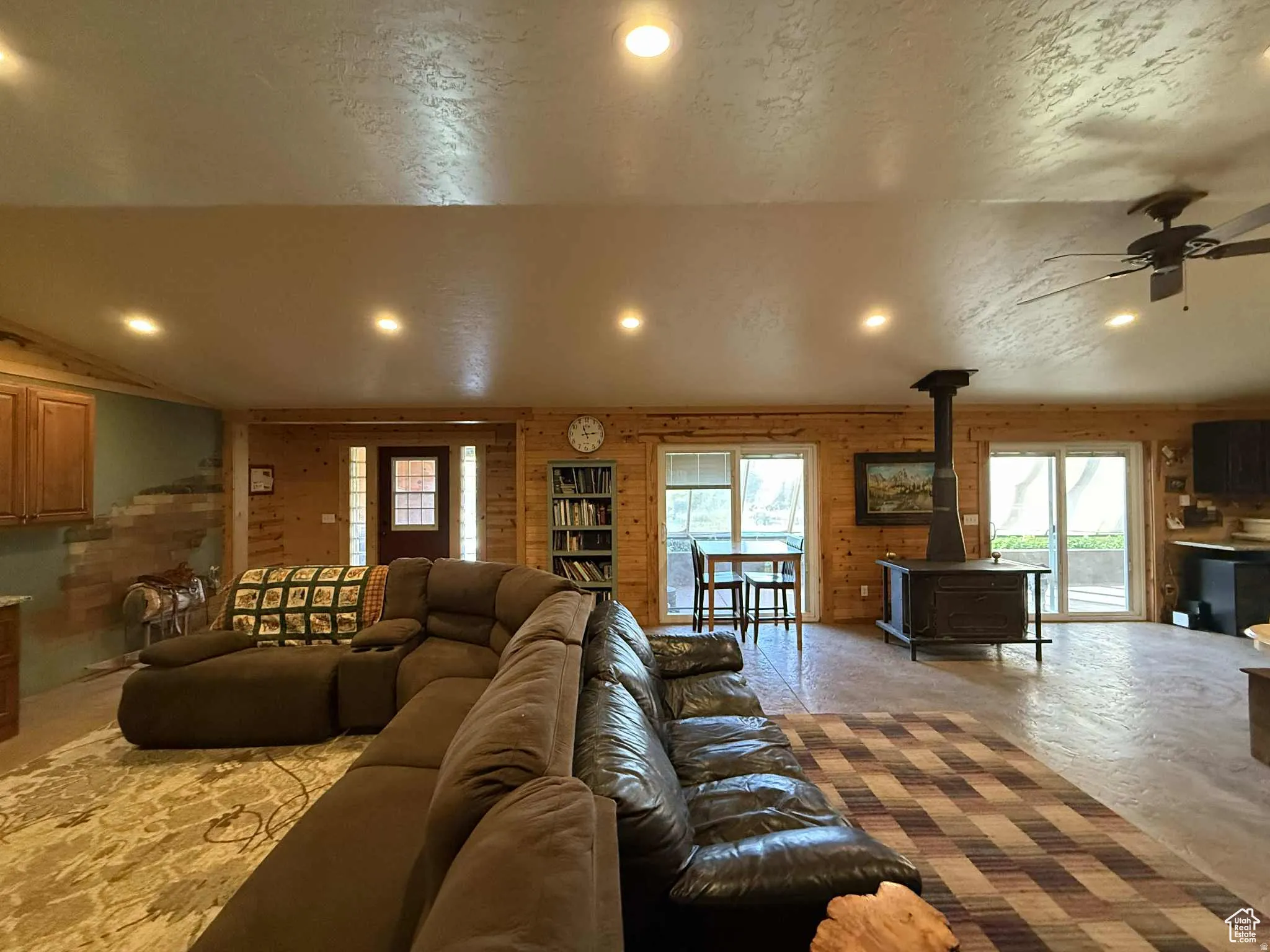 Living room with a wood stove, vaulted ceiling, a ceiling fan, recessed lighting, and healthy amount of natural light