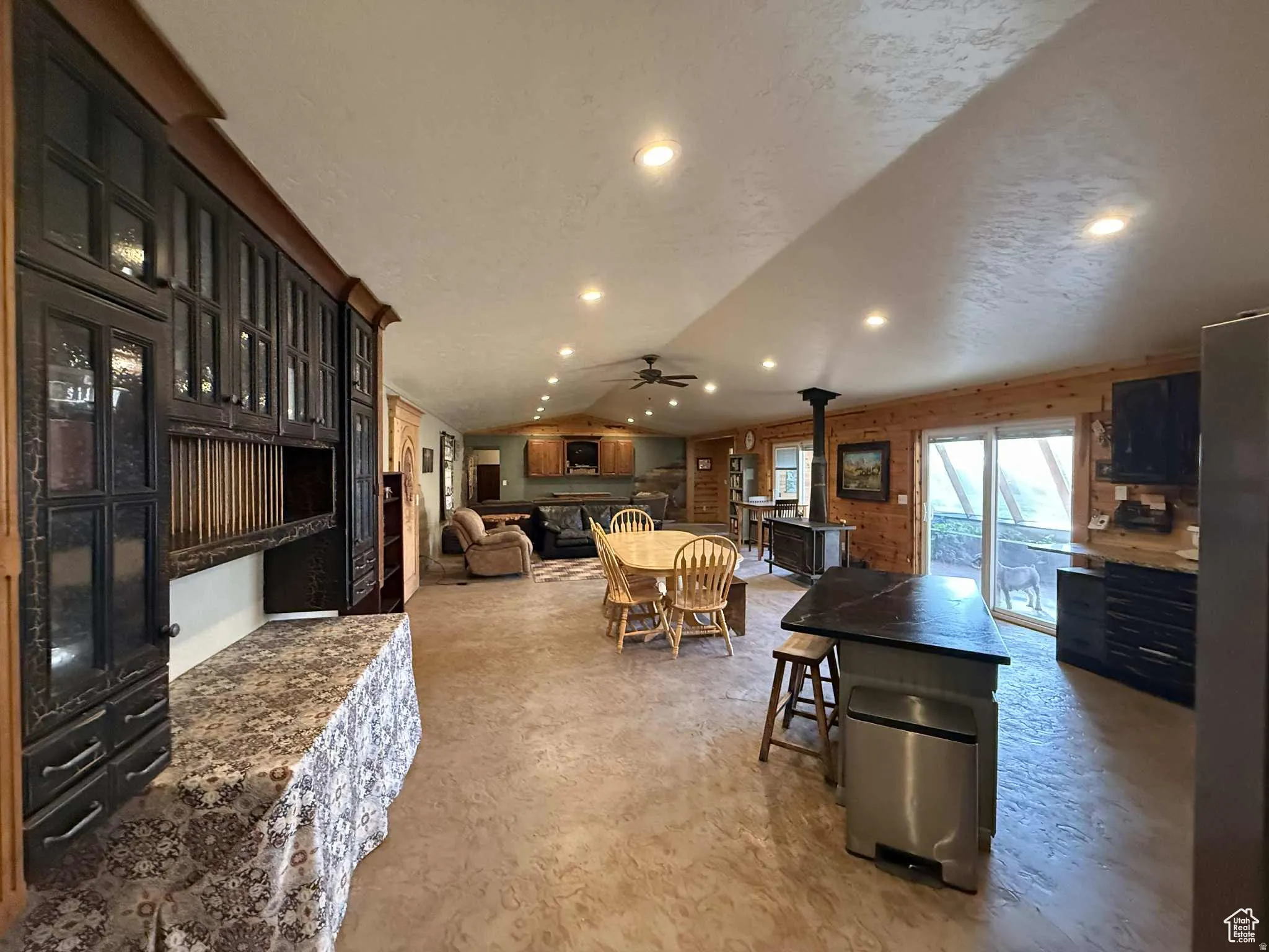 Dining area featuring a wood stove, lofted ceiling, a textured ceiling, and recessed lighting