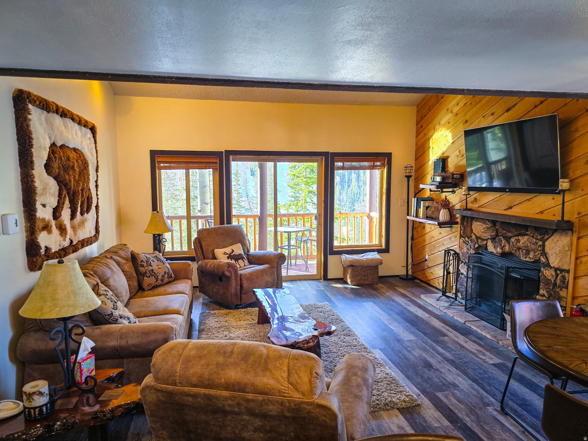 Living area with a fireplace, wood walls, wood finished floors, and a textured ceiling