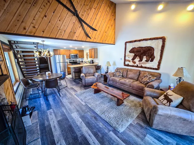 Living area with dark wood-style floors, a chandelier, and a high ceiling