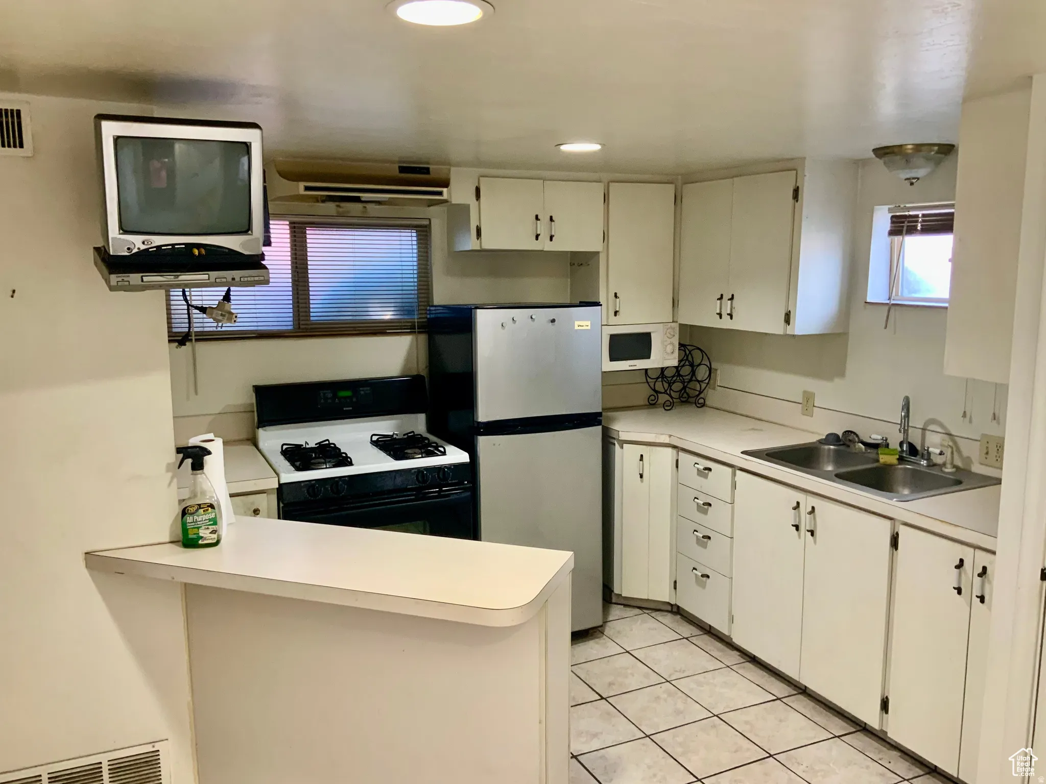 Kitchen featuring range with gas stovetop, light countertops, a peninsula, white cabinets, and recessed lighting
