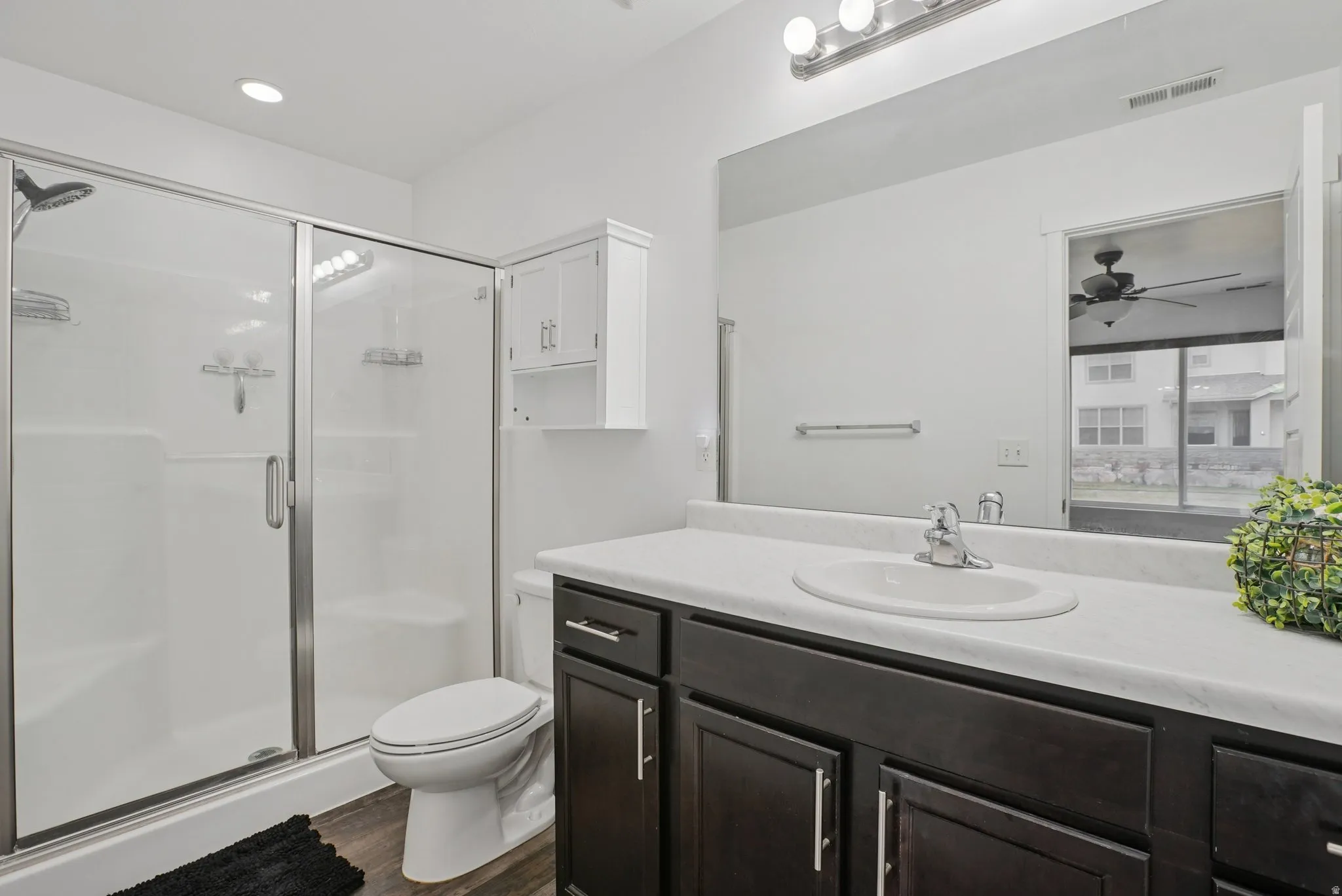 Bathroom featuring a stall shower, vanity, dark wood-style flooring, and ceiling fan