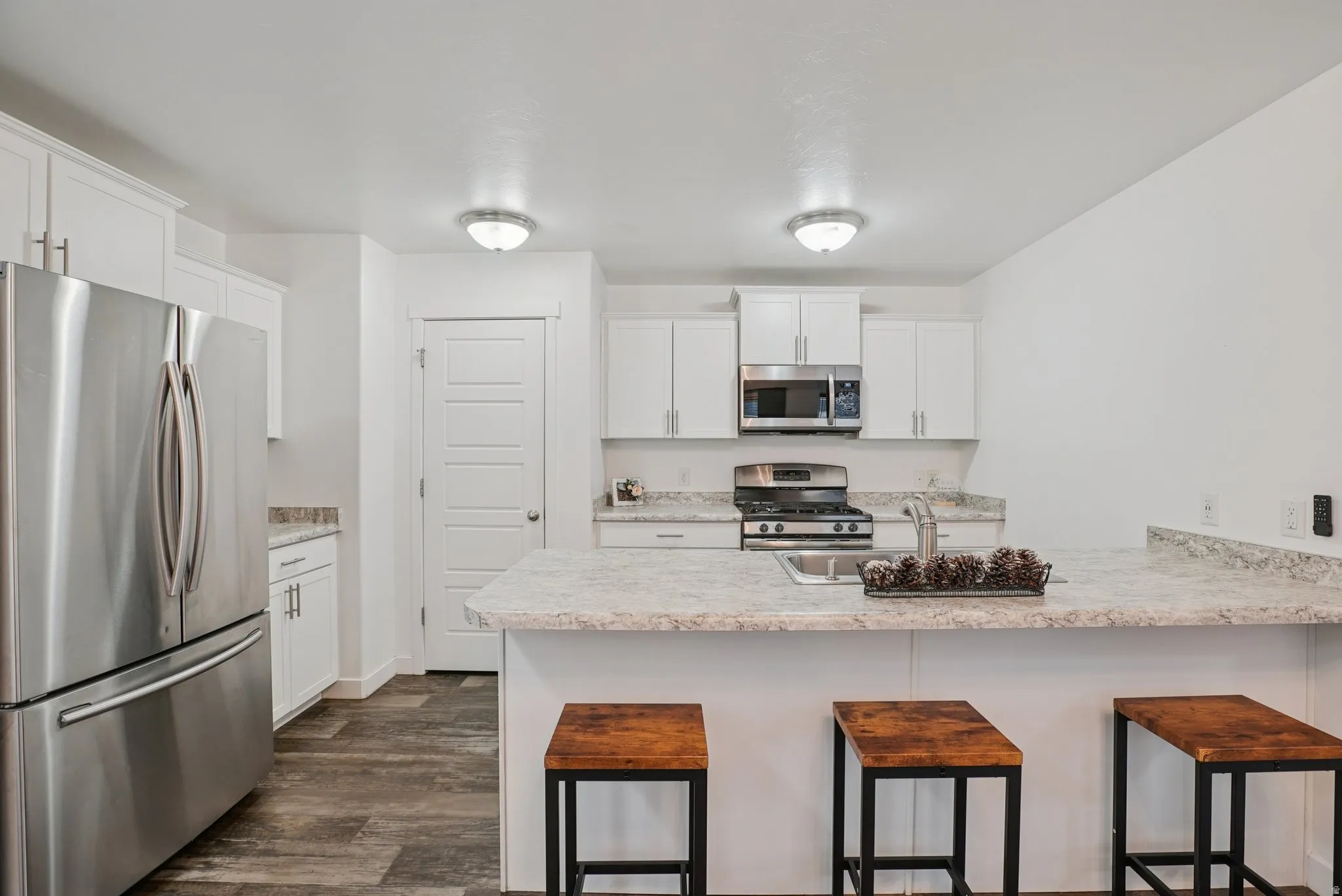 Kitchen with appliances with stainless steel finishes, a breakfast bar area, a peninsula, and white cabinets