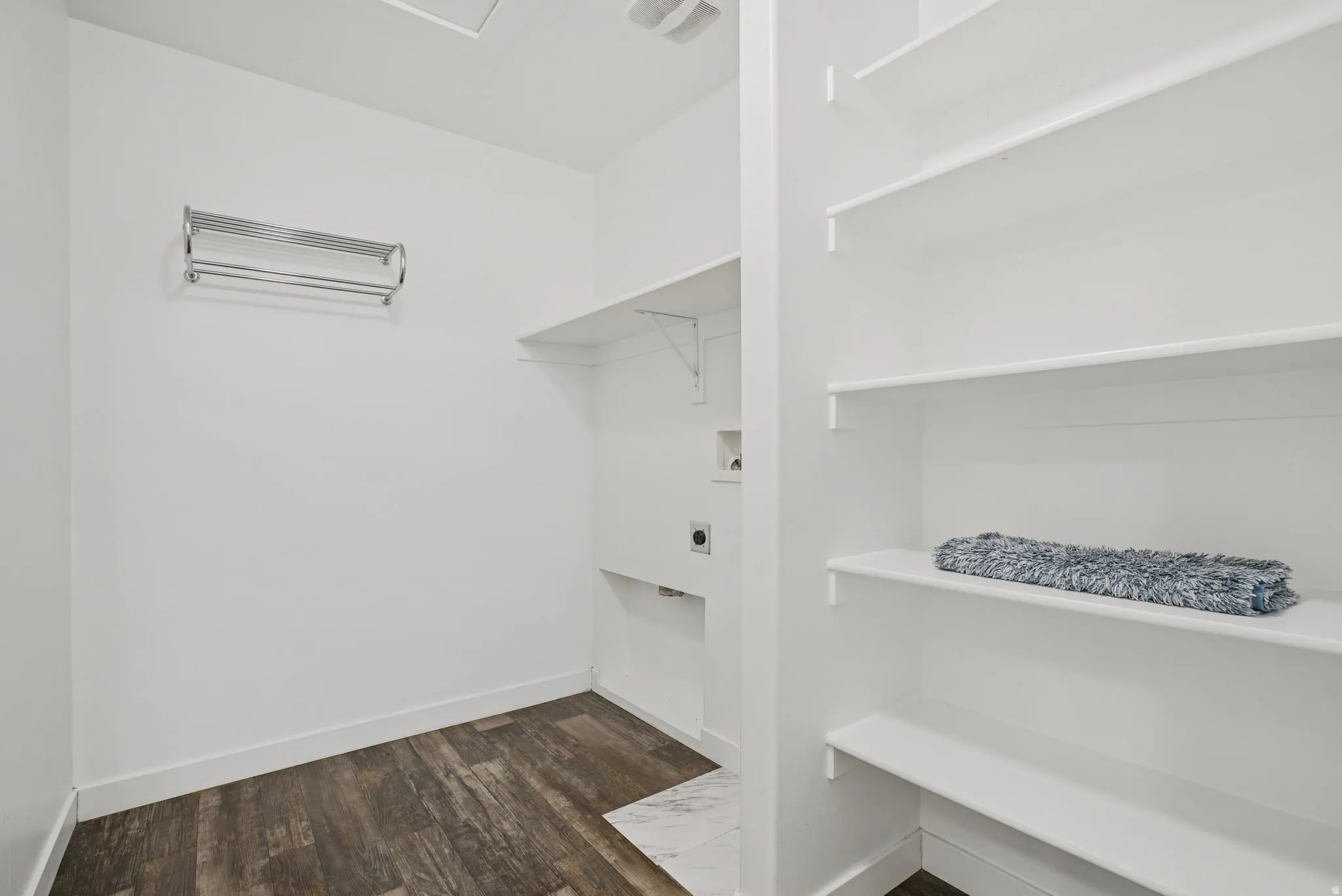 Walk in closet with dark wood-style floors