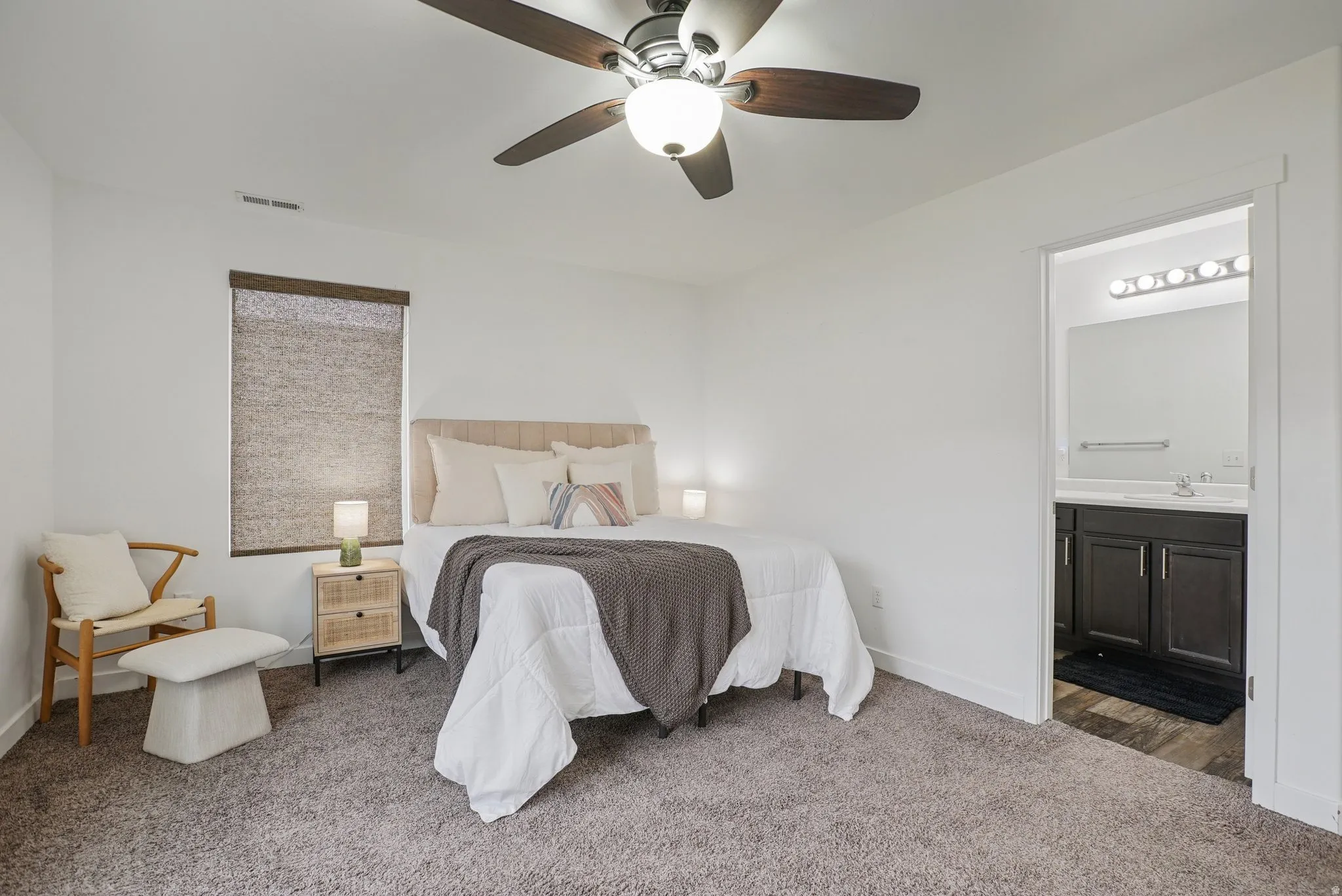 Carpeted bedroom featuring ceiling fan and ensuite bathroom