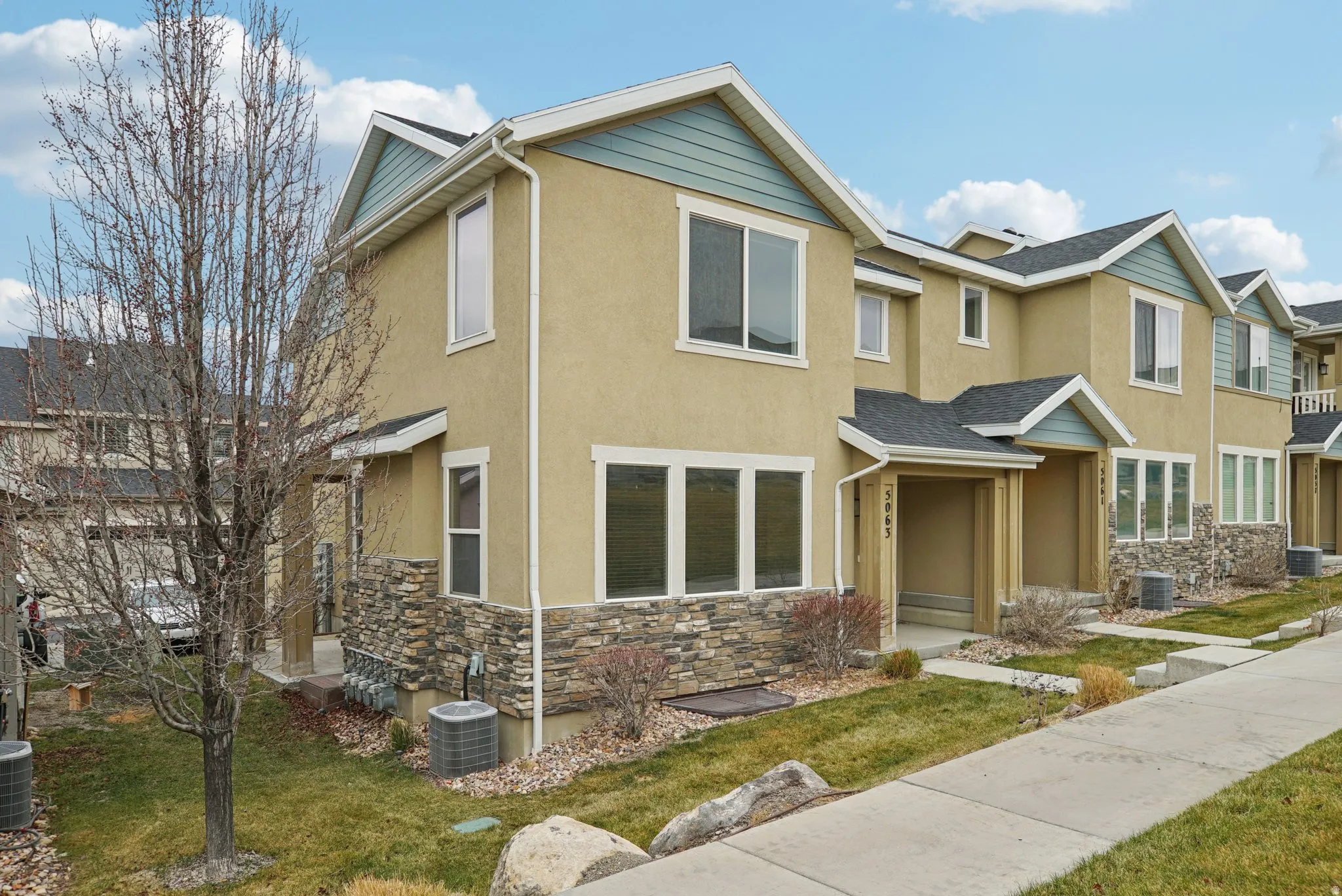 Traditional home featuring stone siding, a front lawn, and stucco siding
