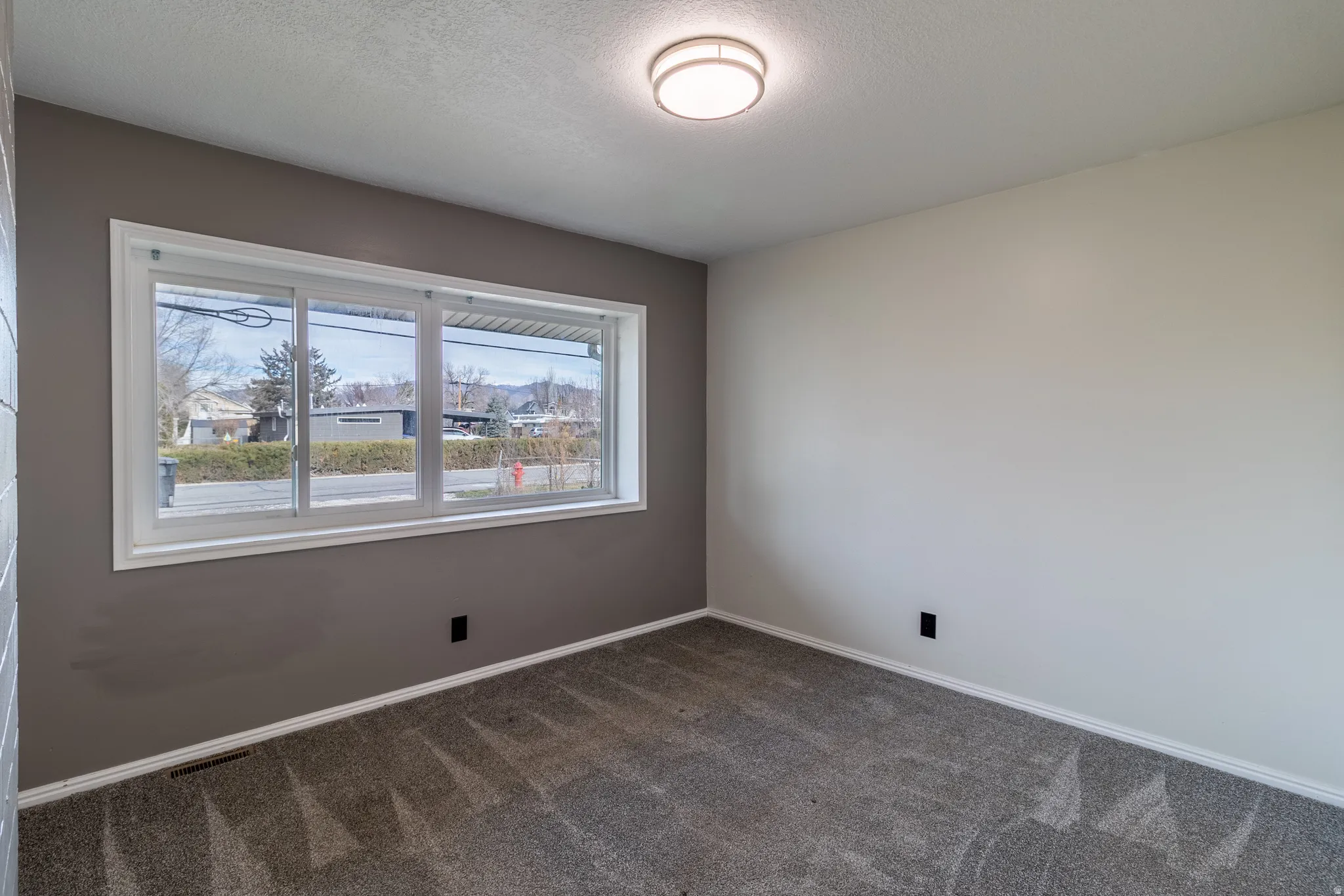Unfurnished room featuring a textured ceiling and dark carpet