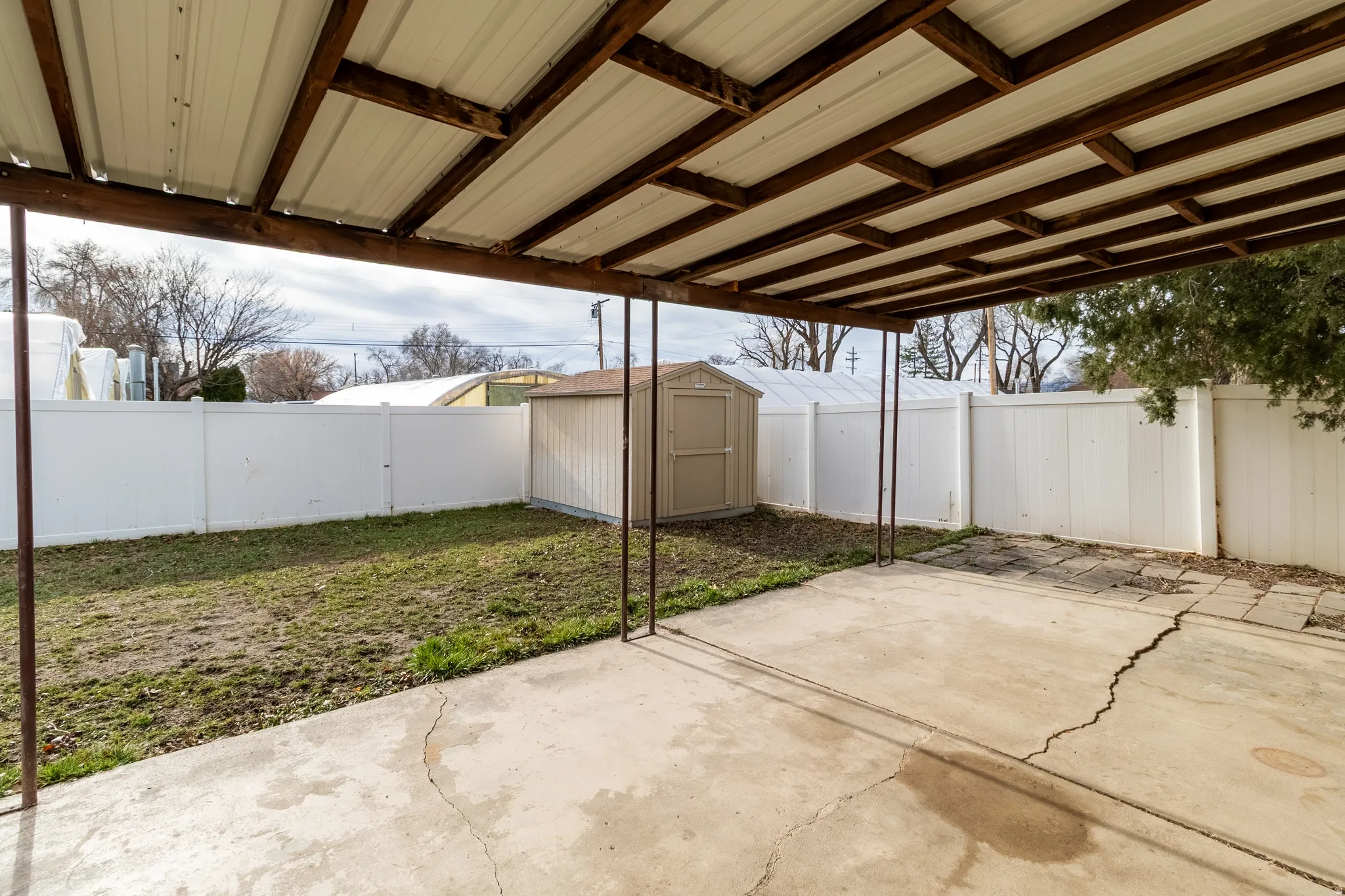 Fenced backyard featuring a storage shed and a patio area