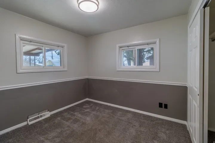 Empty room with plenty of natural light and dark carpet
