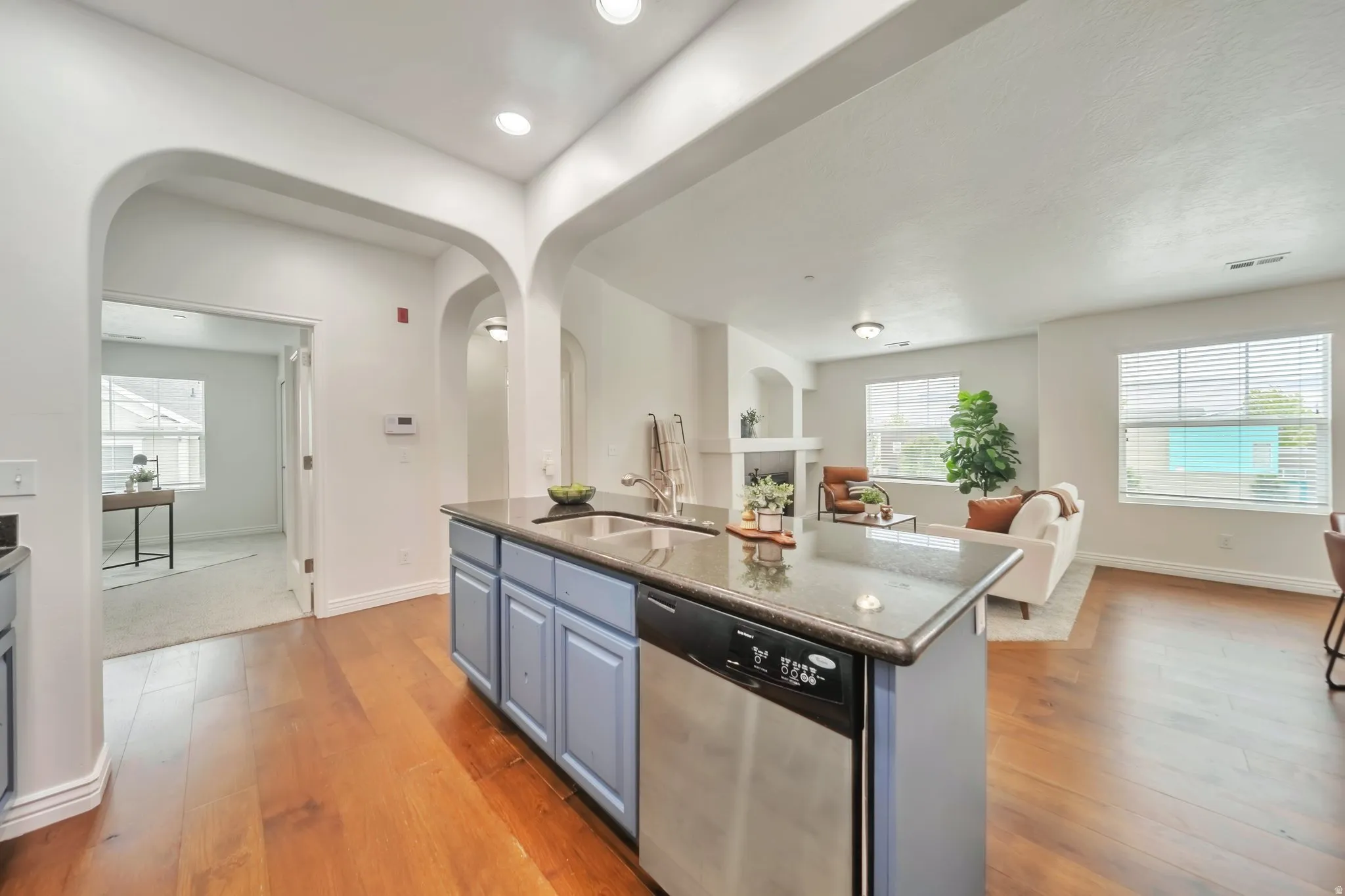Kitchen with dishwasher, an island with sink, open floor plan, light wood-type flooring, and recessed lighting