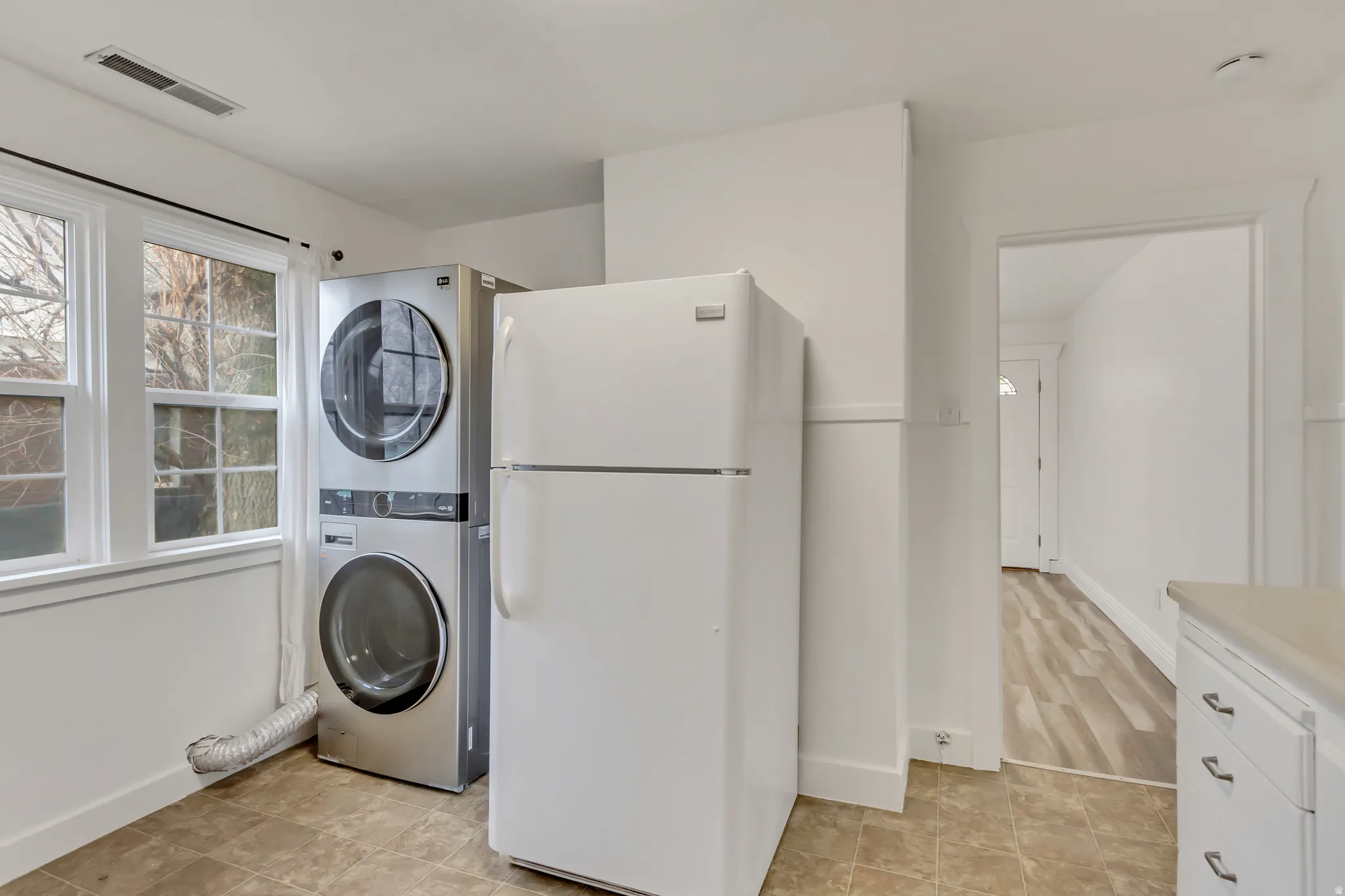 Laundry room featuring stacked washing machine and dryer and baseboards