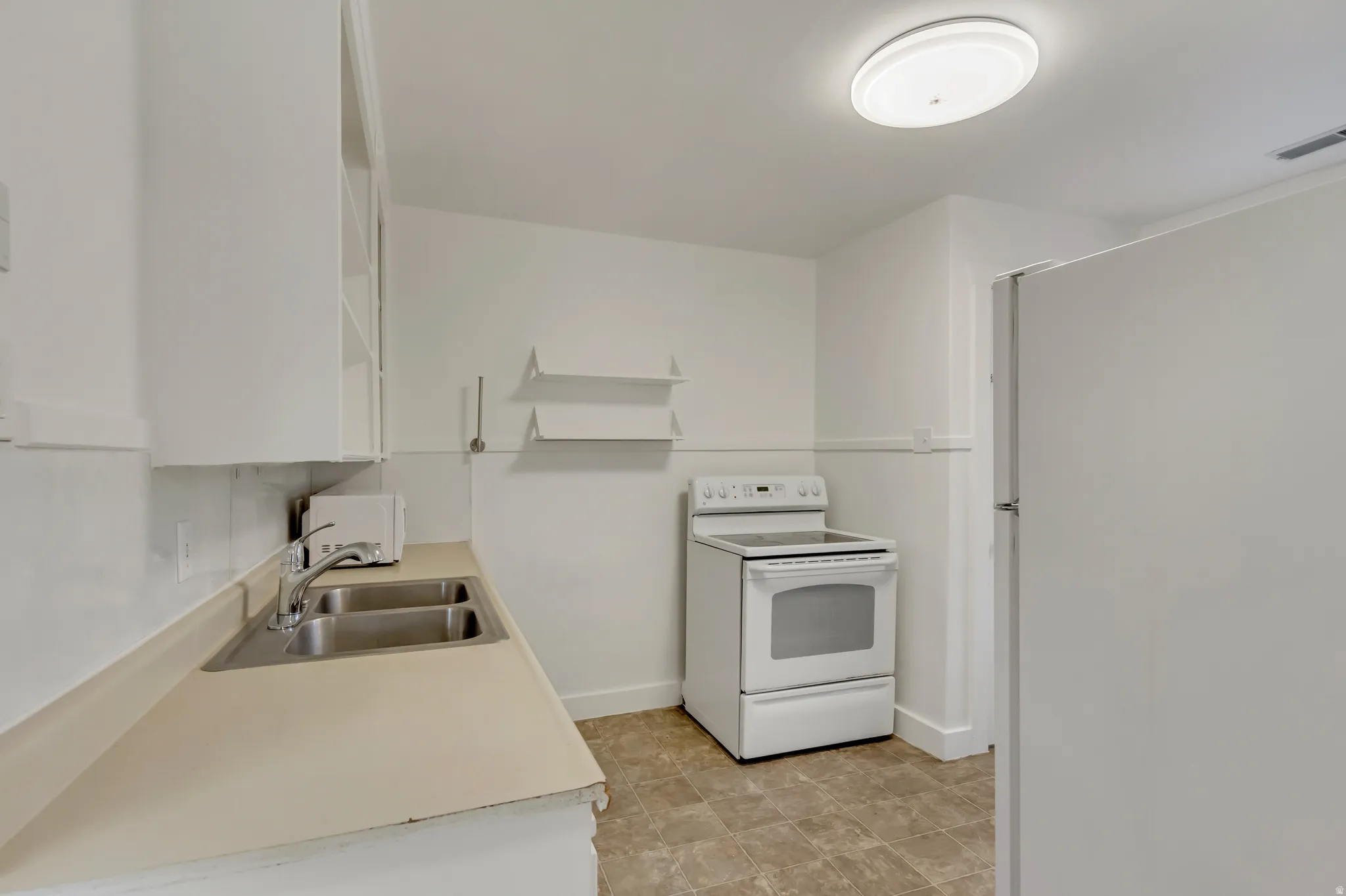 Kitchen featuring white appliances, open shelves, light countertops, and white cabinetry
