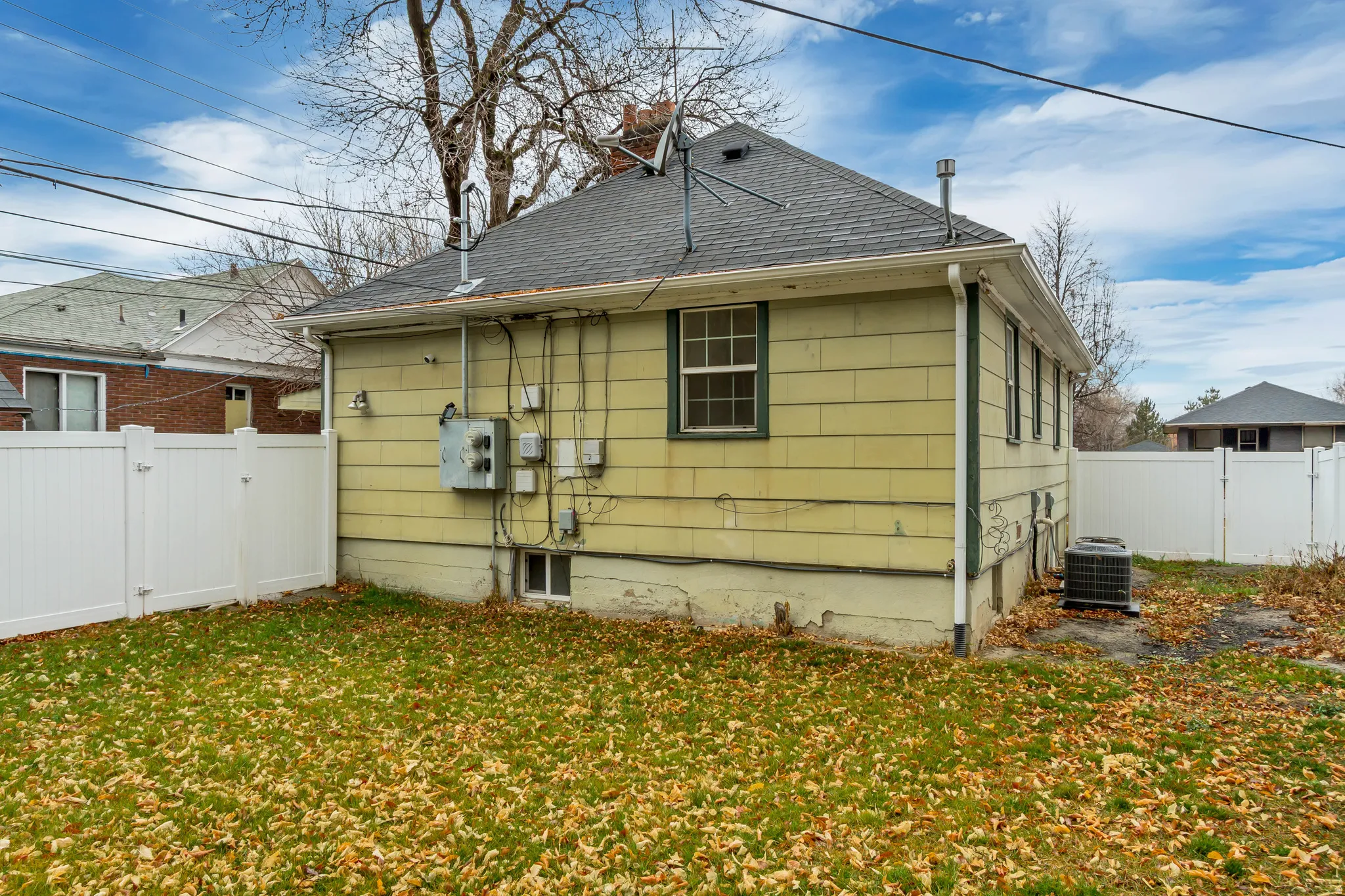 View of side of home featuring a fenced backyard, a shingled roof, and a gate