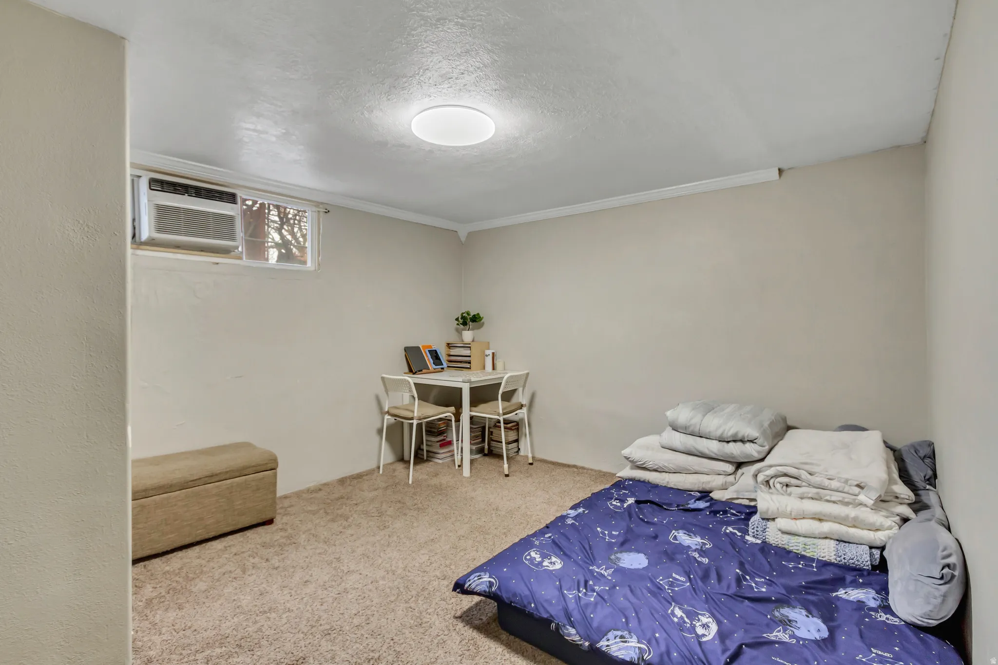 Carpeted bedroom featuring a textured ceiling and an AC wall unit