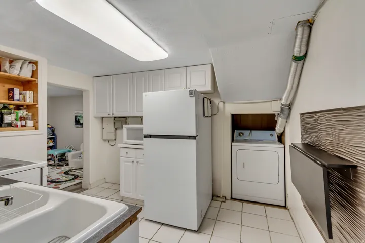 Kitchen featuring white cabinets, washer / dryer, white appliances, and light tile patterned flooring