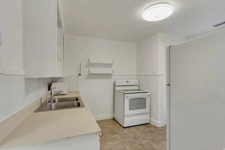 Kitchen featuring white appliances, open shelves, light countertops, and white cabinetry