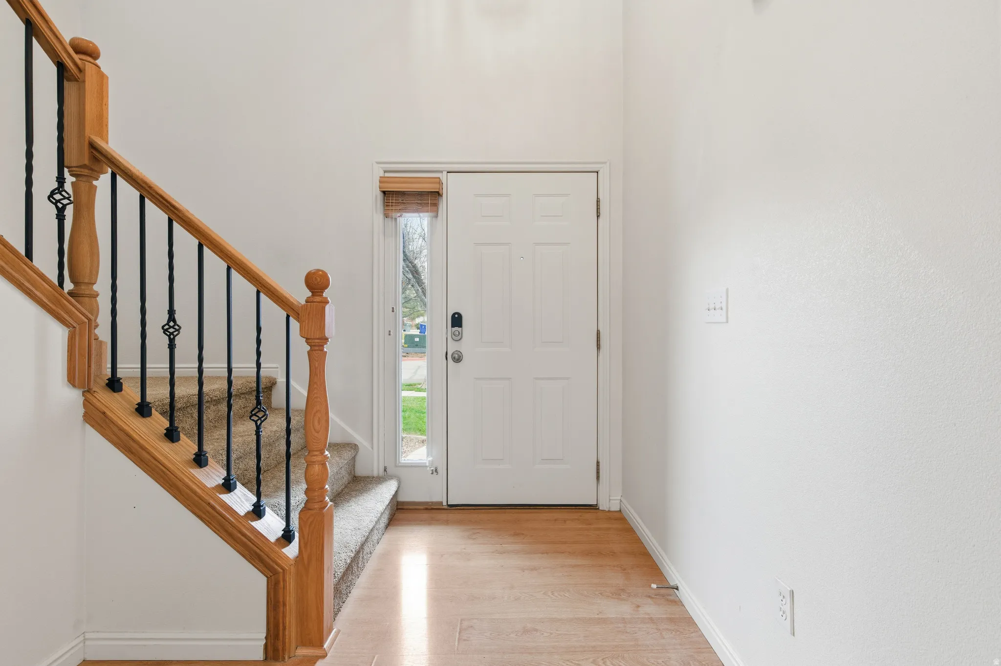 Foyer with light wood-style floors, stairway, and a high ceiling