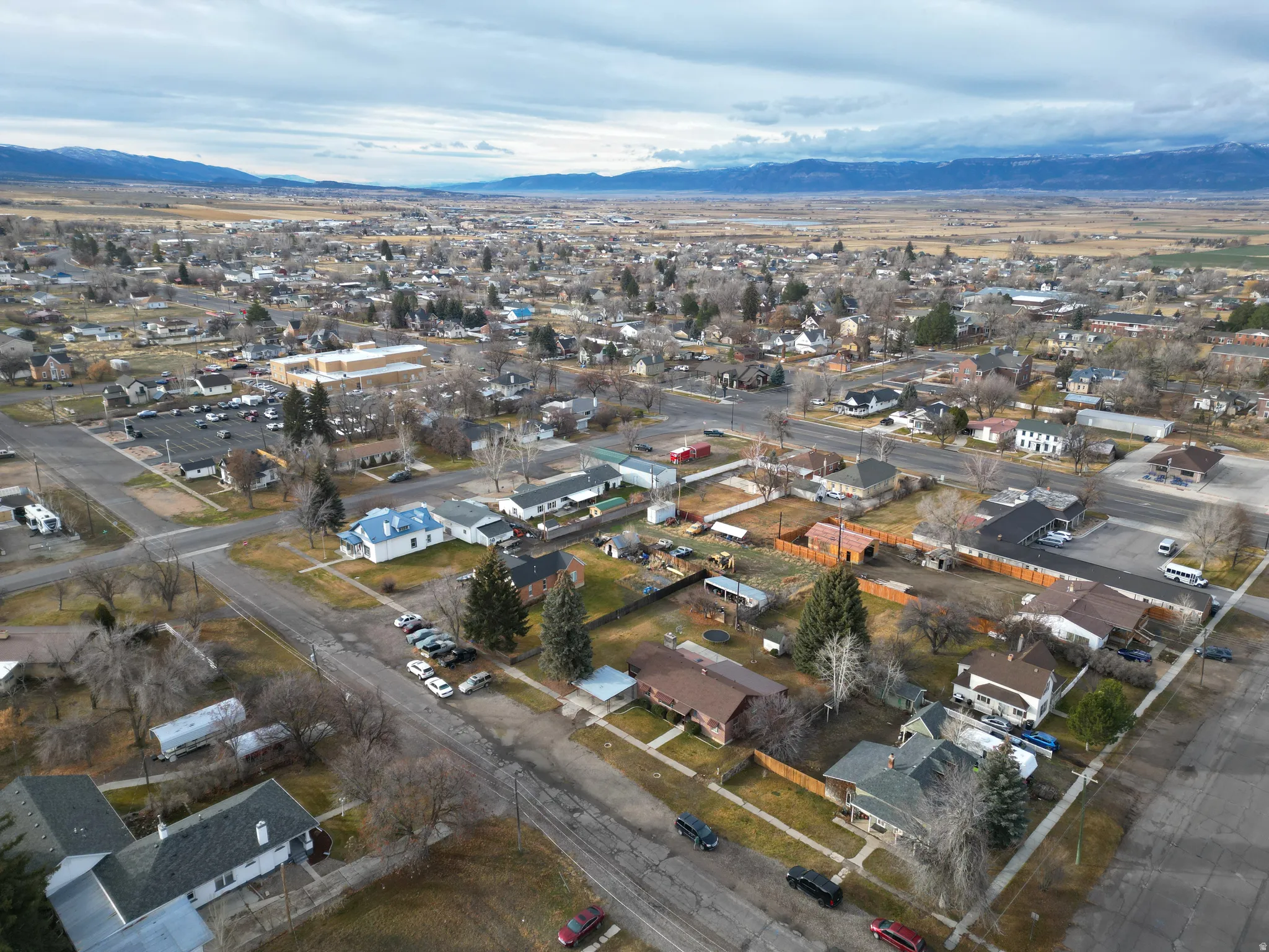 Aerial view of property and surrounding area featuring mountains and nearby suburban area
