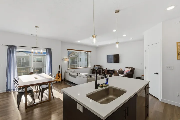 Kitchen with open floor plan, a center island with sink, decorative light fixtures, dark brown cabinets, and recessed lighting