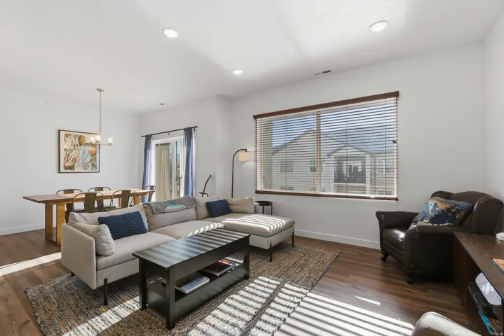 Living room with dark wood-type flooring, a chandelier, and recessed lighting