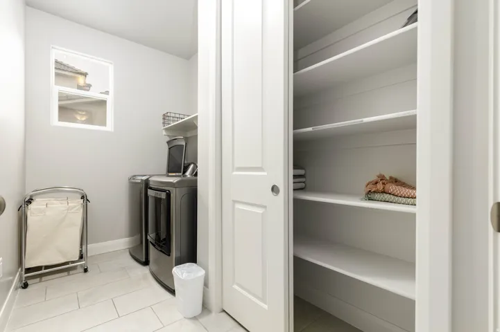 Laundry room with separate washer and dryer and light tile patterned floors