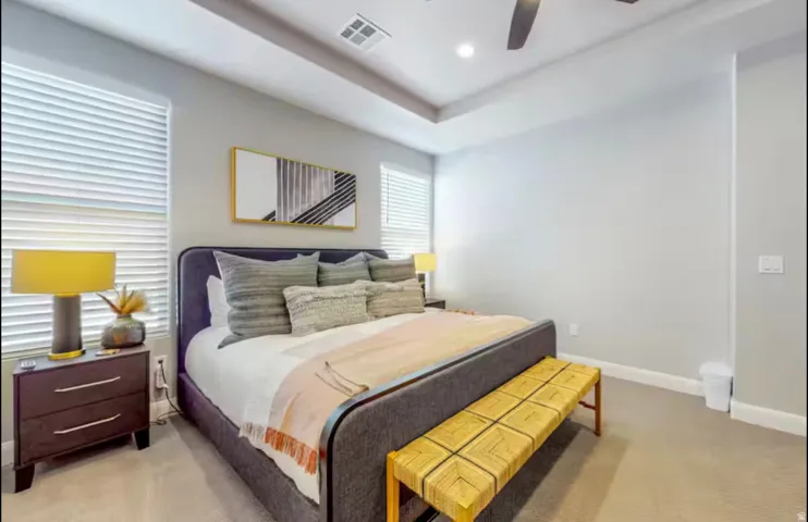 Primary bedroom featuring light colored carpet, a ceiling fan, recessed lighting, and a tray ceiling