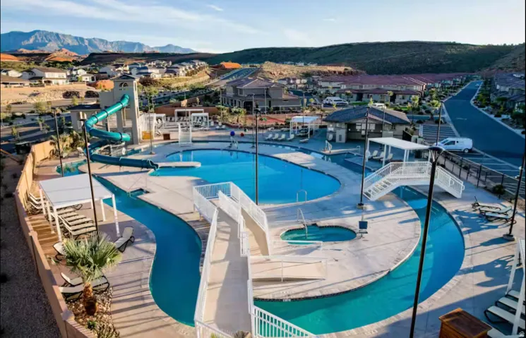Community pool with a community hot tub, a water slide, lazy river, a mountain view, and a residential view