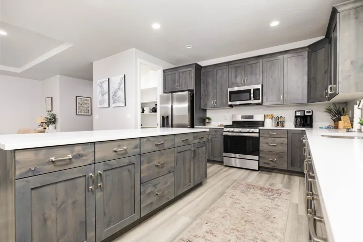Kitchen featuring appliances with stainless steel finishes, recessed lighting, light wood-style flooring, dark brown cabinetry, and light stone countertops