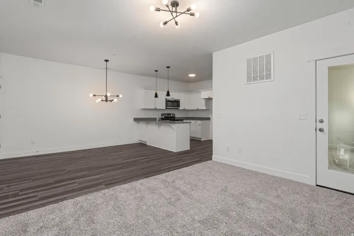 Unfurnished living room featuring a chandelier, dark colored carpet, and a textured ceiling